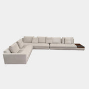 The Walter Knoll Tama Living 3 Piece Modular Sofa by Walter Knoll features an L-shaped design in light gray luxury fabric, matching cushions, and a built-in wooden side table on the right.