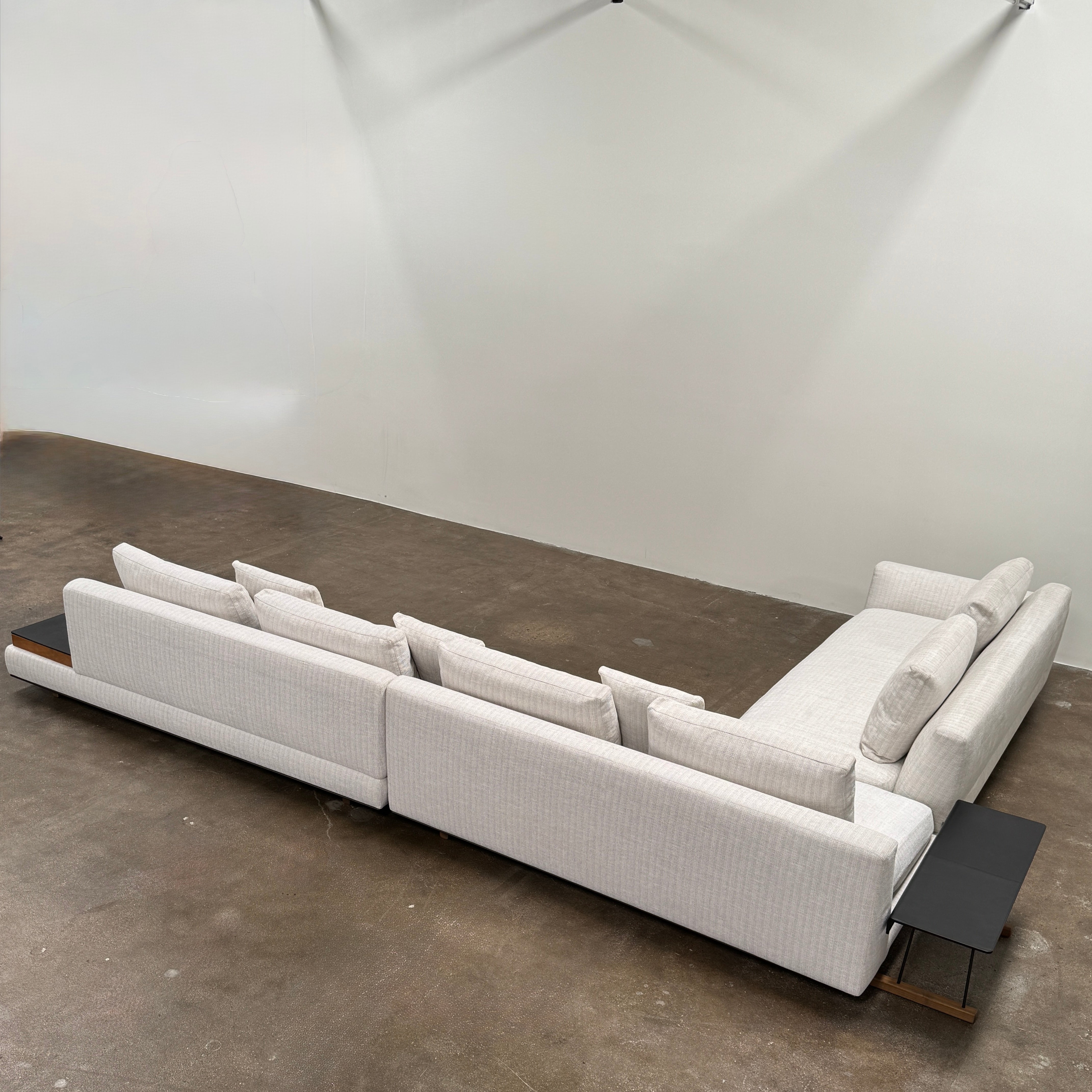 The Walter Knoll Tama Living 3 Piece Modular Sofa by Walter Knoll features an L-shaped design in light gray luxury fabric, matching cushions, and a built-in wooden side table on the right.