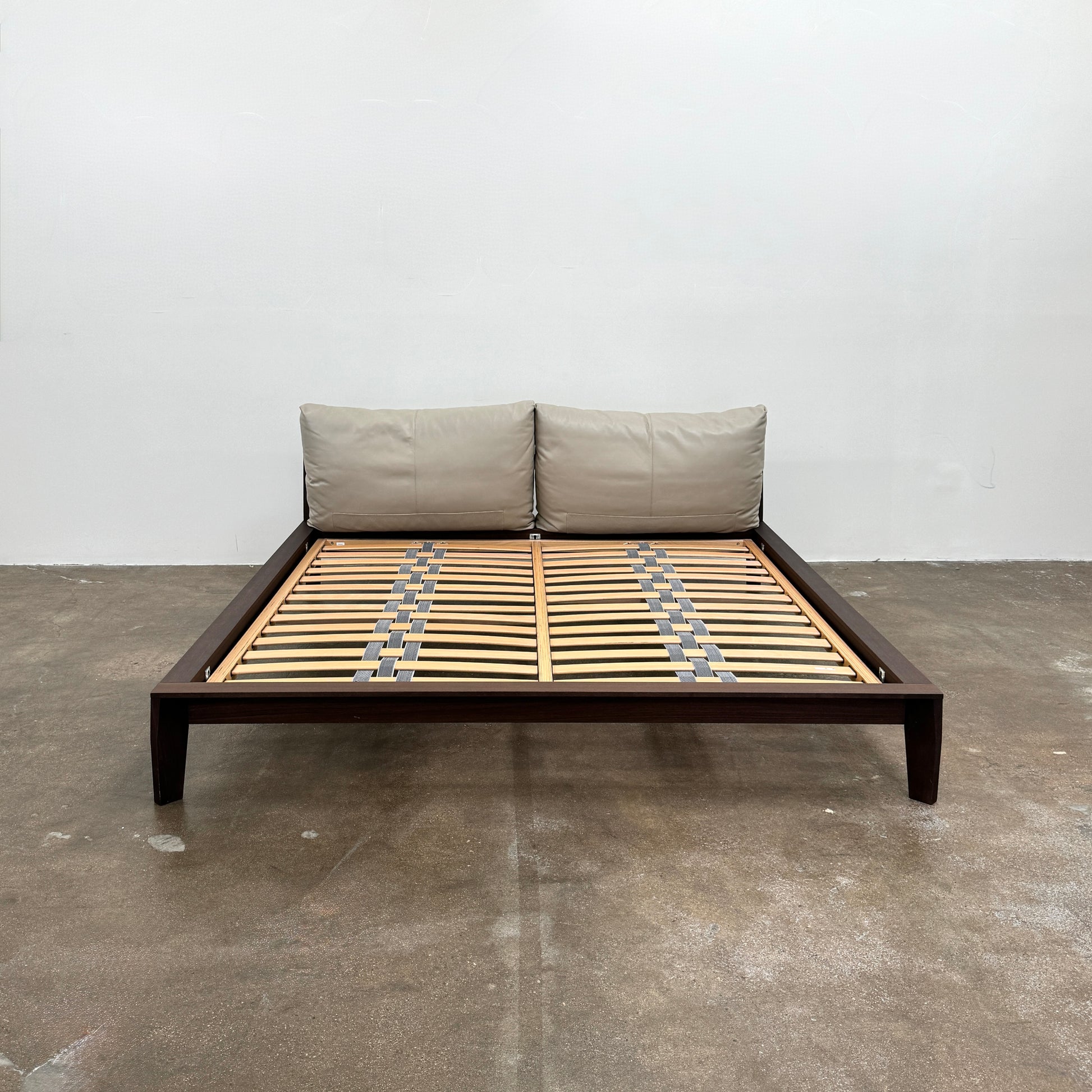 The Molteni&C Wish King Size Bed by Molteni & C features a solid wood frame with a slatted base, dark brown legs, and two large beige headboard cushions. Shown on a white background, it’s ideal for stylish and comfortable bedrooms.
