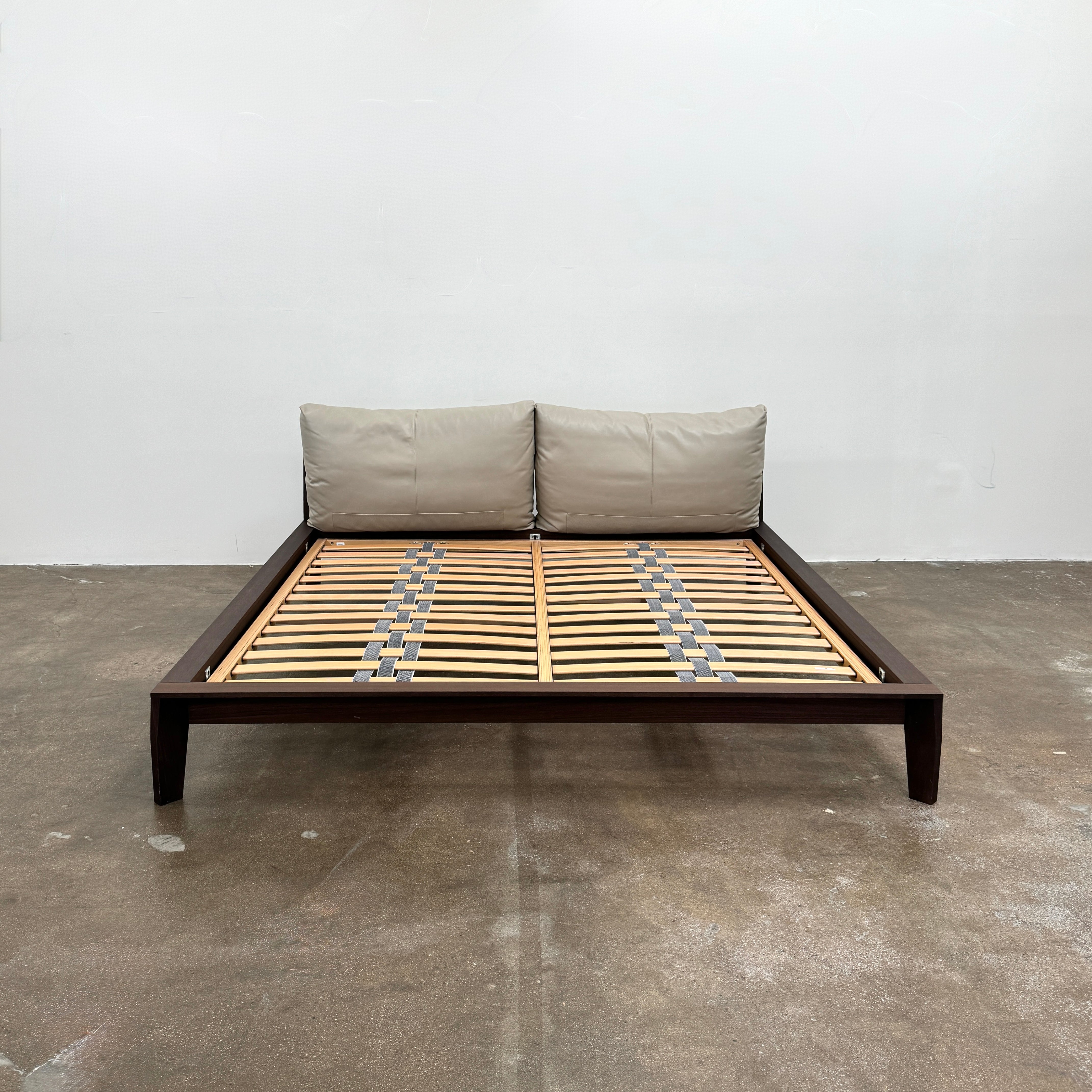 The Molteni&C Wish King Size Bed by Molteni & C features a solid wood frame with a slatted base, dark brown legs, and two large beige headboard cushions. Shown on a white background, it’s ideal for stylish and comfortable bedrooms.