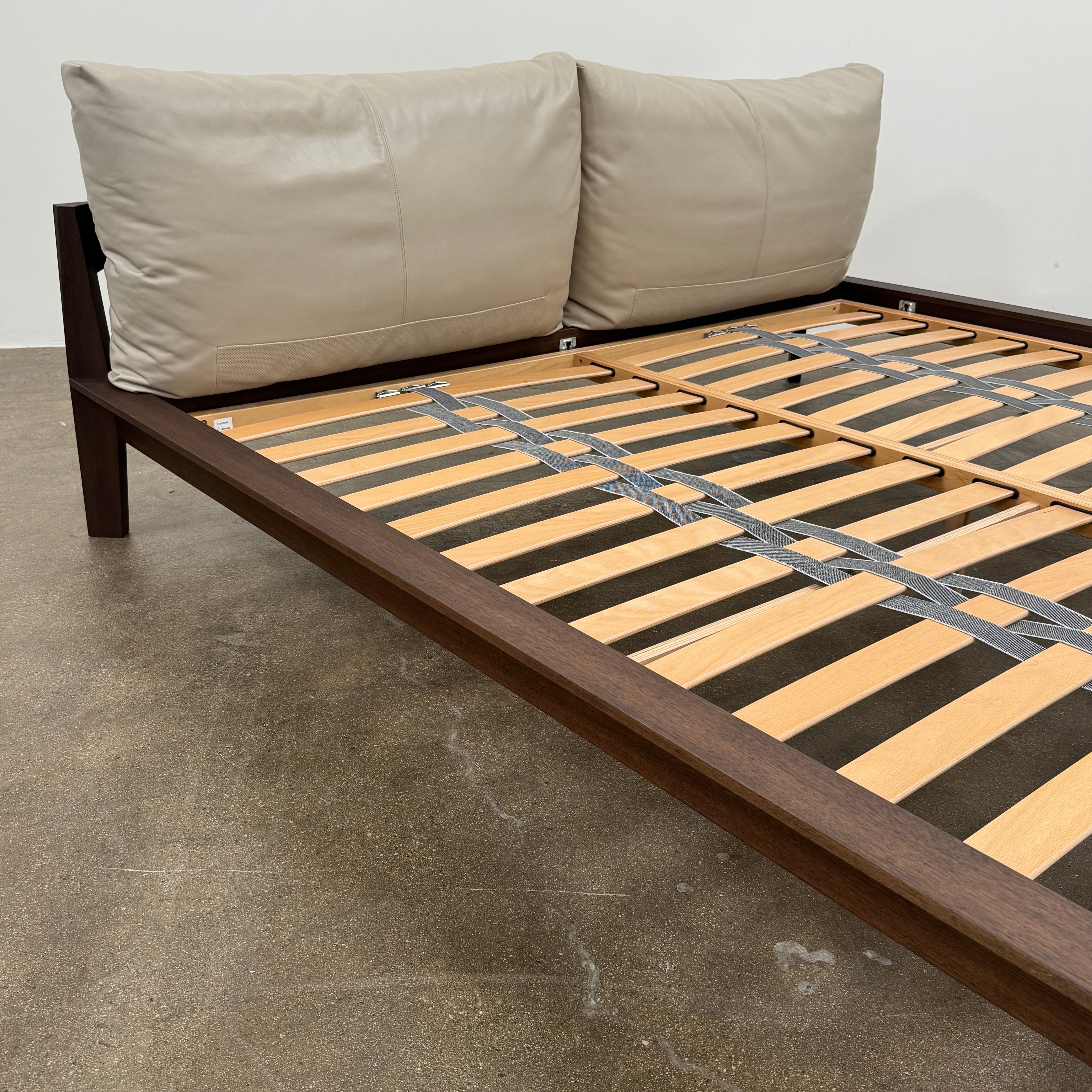 The Molteni&C Wish King Size Bed by Molteni & C features a solid wood frame with a slatted base, dark brown legs, and two large beige headboard cushions. Shown on a white background, it’s ideal for stylish and comfortable bedrooms.
