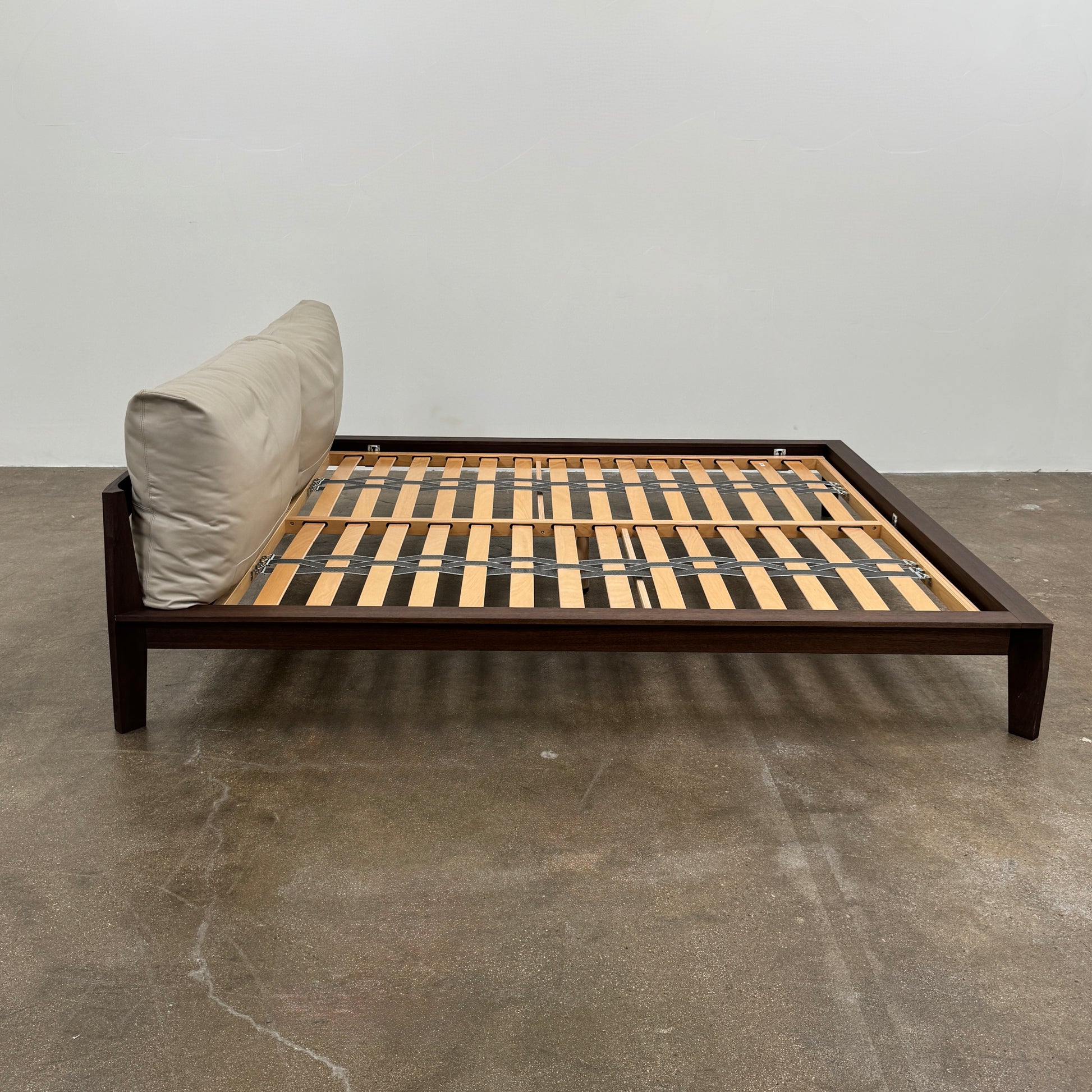 The Molteni&C Wish King Size Bed by Molteni & C features a solid wood frame with a slatted base, dark brown legs, and two large beige headboard cushions. Shown on a white background, it’s ideal for stylish and comfortable bedrooms.