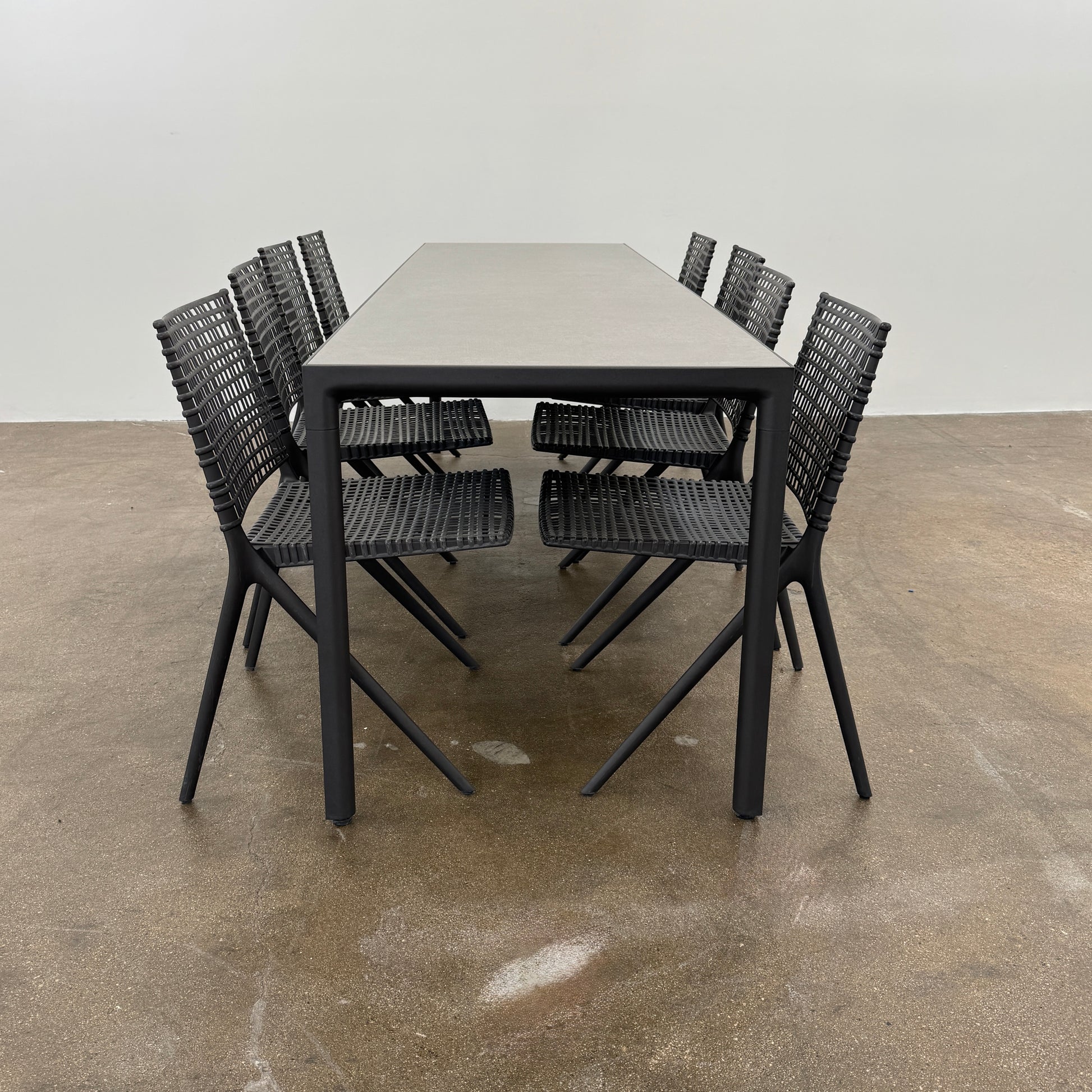 The Tribu Illum Outdoor Dining Table with 8 Chairs by Modern Resale features a sleek black finish and matching seating, set against a plain white background—an elegant choice for any modern outdoor space.