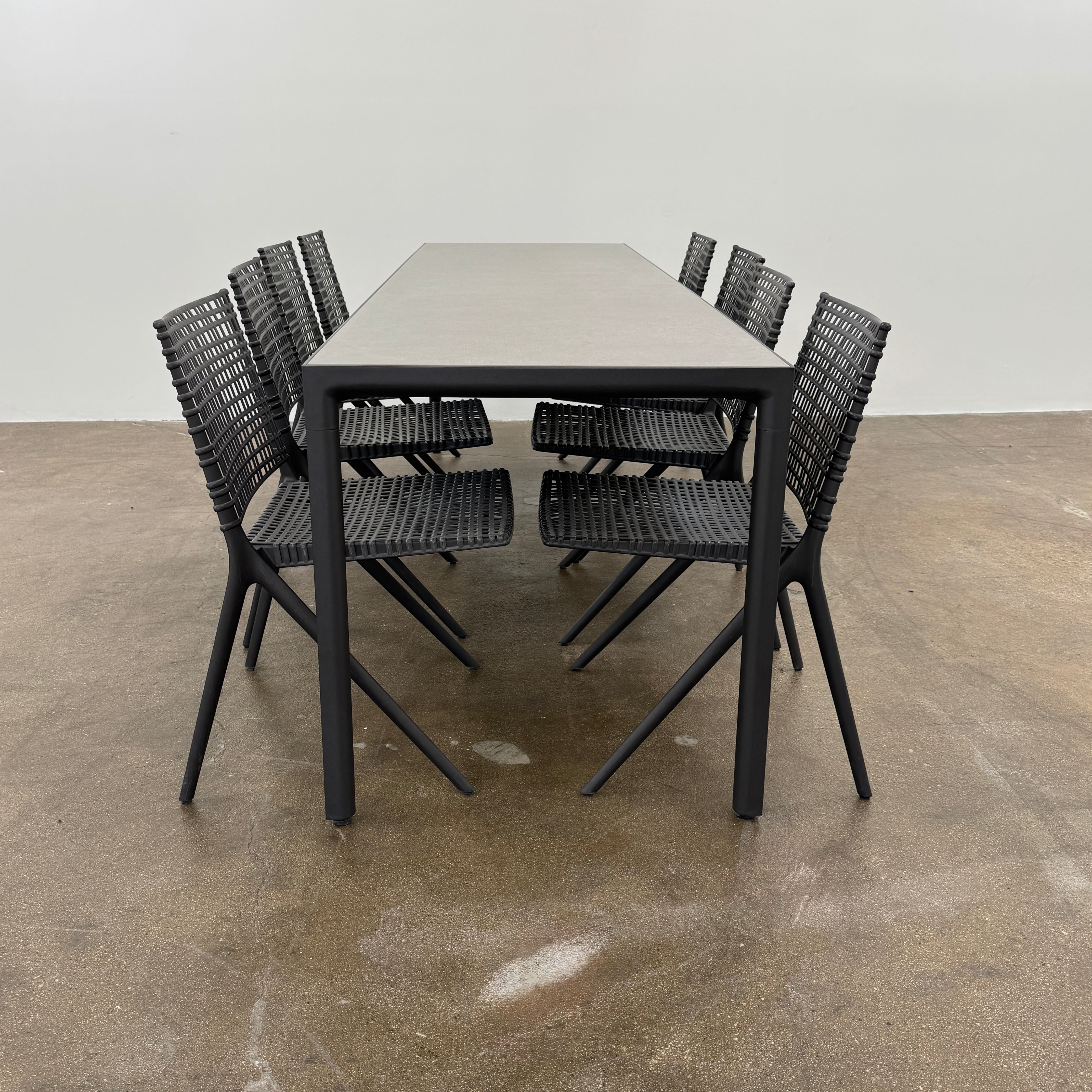 The Tribu Illum Outdoor Dining Table with 8 Chairs by Modern Resale features a sleek black finish and matching seating, set against a plain white background—an elegant choice for any modern outdoor space.