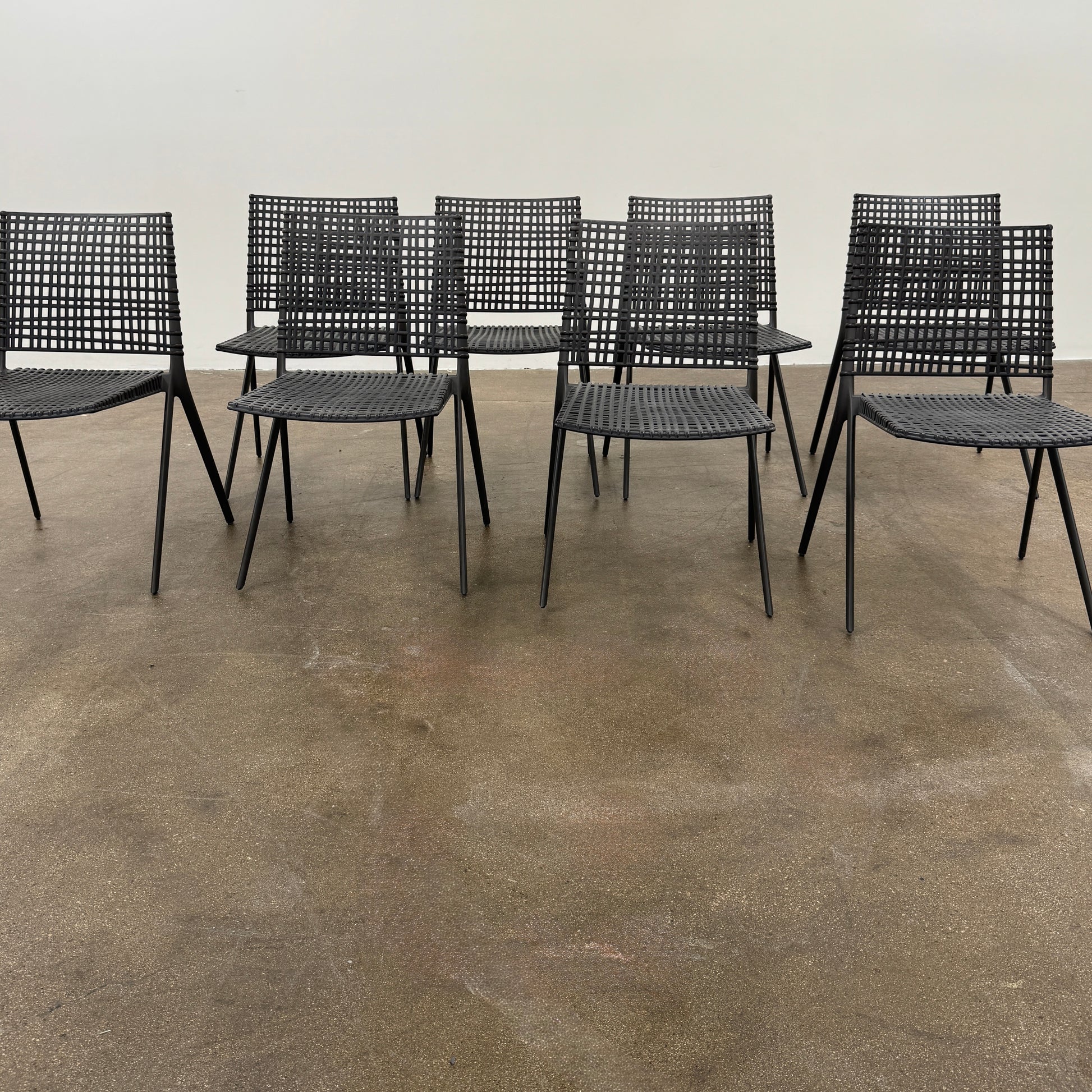 The Tribu Illum Outdoor Dining Table with 8 Chairs by Modern Resale features a sleek black finish and matching seating, set against a plain white background—an elegant choice for any modern outdoor space.