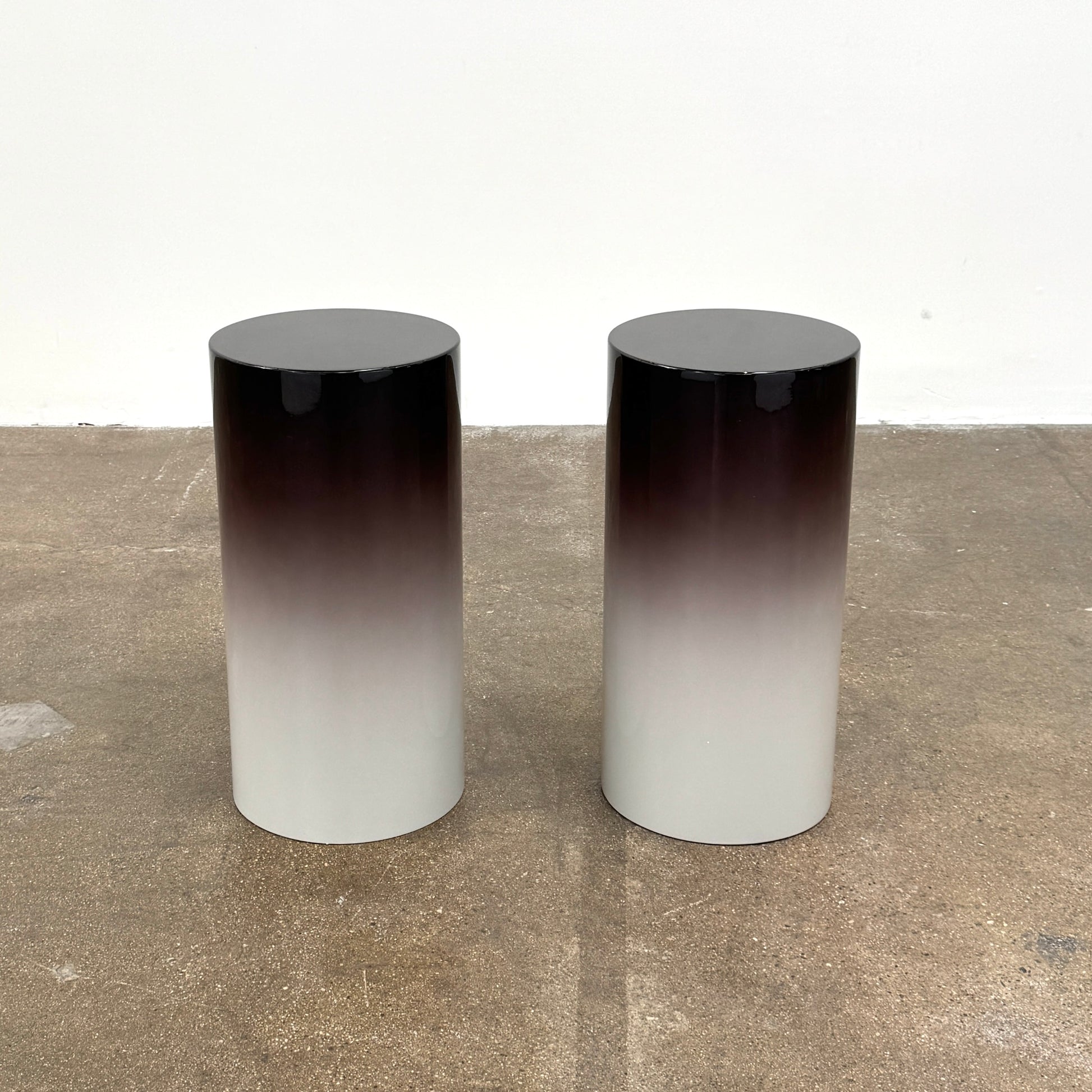 The Minotti Pilotis Accent Table by Minotti features a cylindrical form with a sleek gradient from black to white, adding a modern touch and elevating any contemporary interior furniture collection.