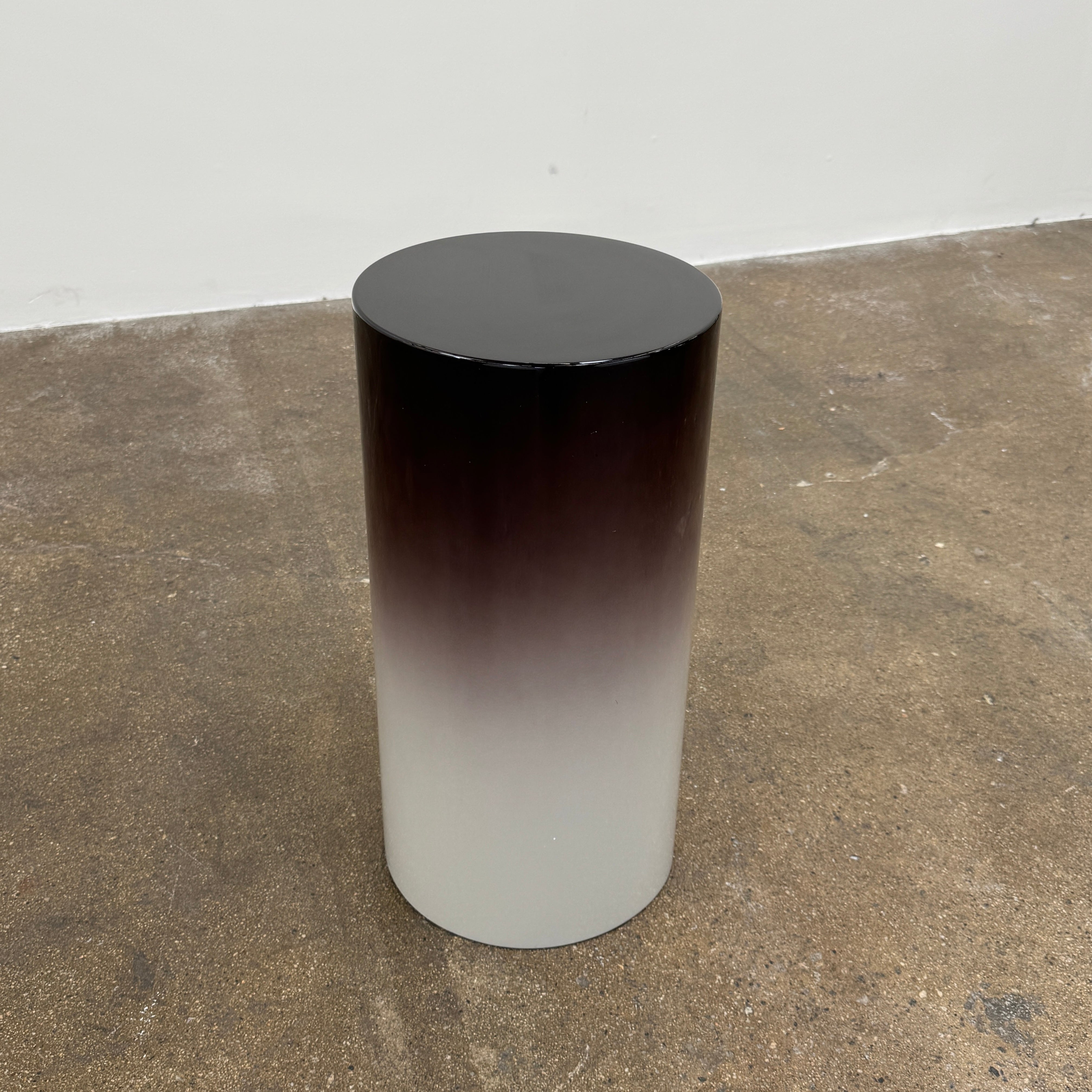 The Minotti Pilotis Accent Table by Minotti features a cylindrical form with a sleek gradient from black to white, adding a modern touch and elevating any contemporary interior furniture collection.
