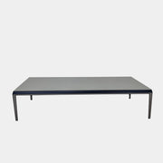 The B&B Italia Michel Coffee Table features a rectangular minimalist design with a flat gray surface and slim black metal legs, showcased against a plain white background.