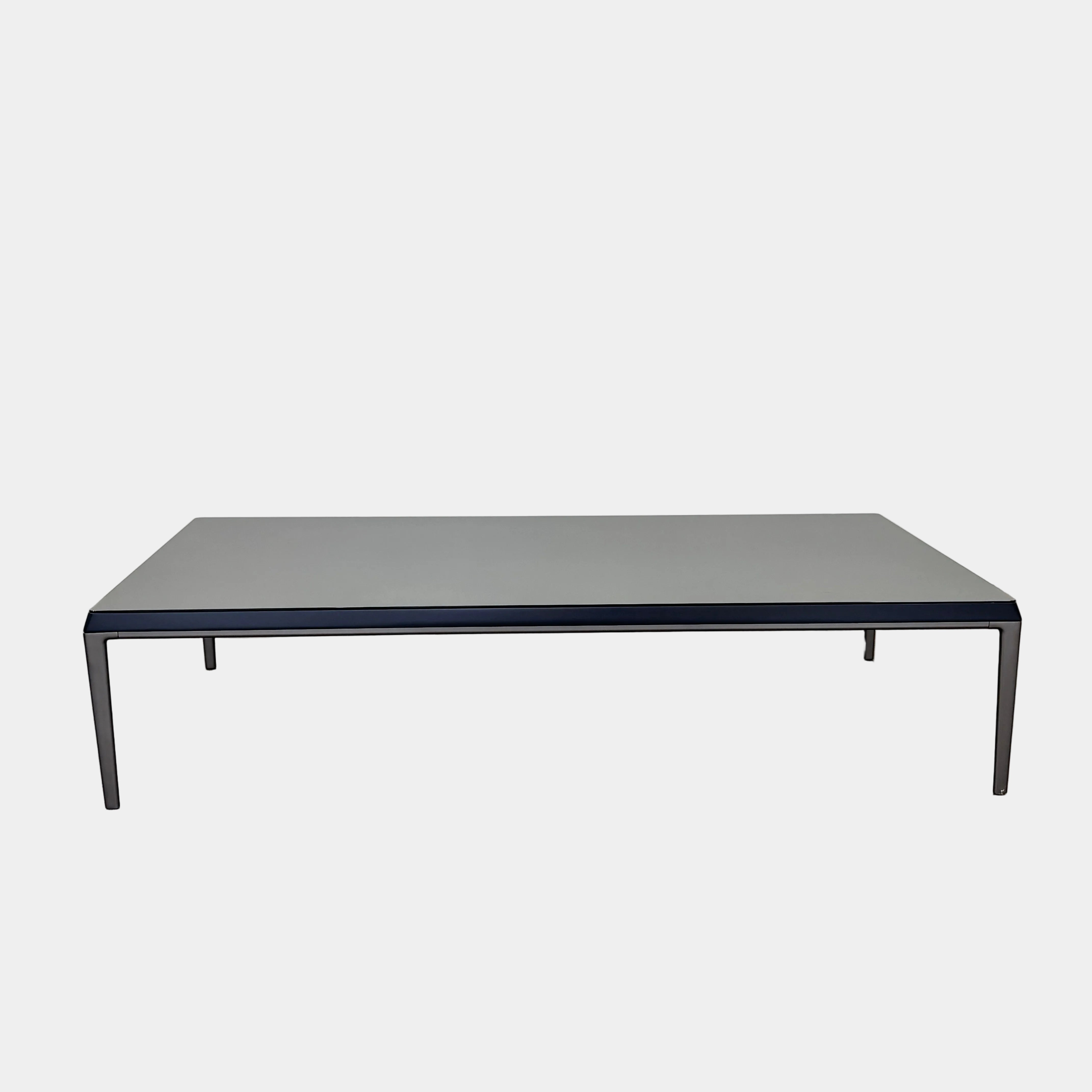 The B&B Italia Michel Coffee Table features a rectangular minimalist design with a flat gray surface and slim black metal legs, showcased against a plain white background.