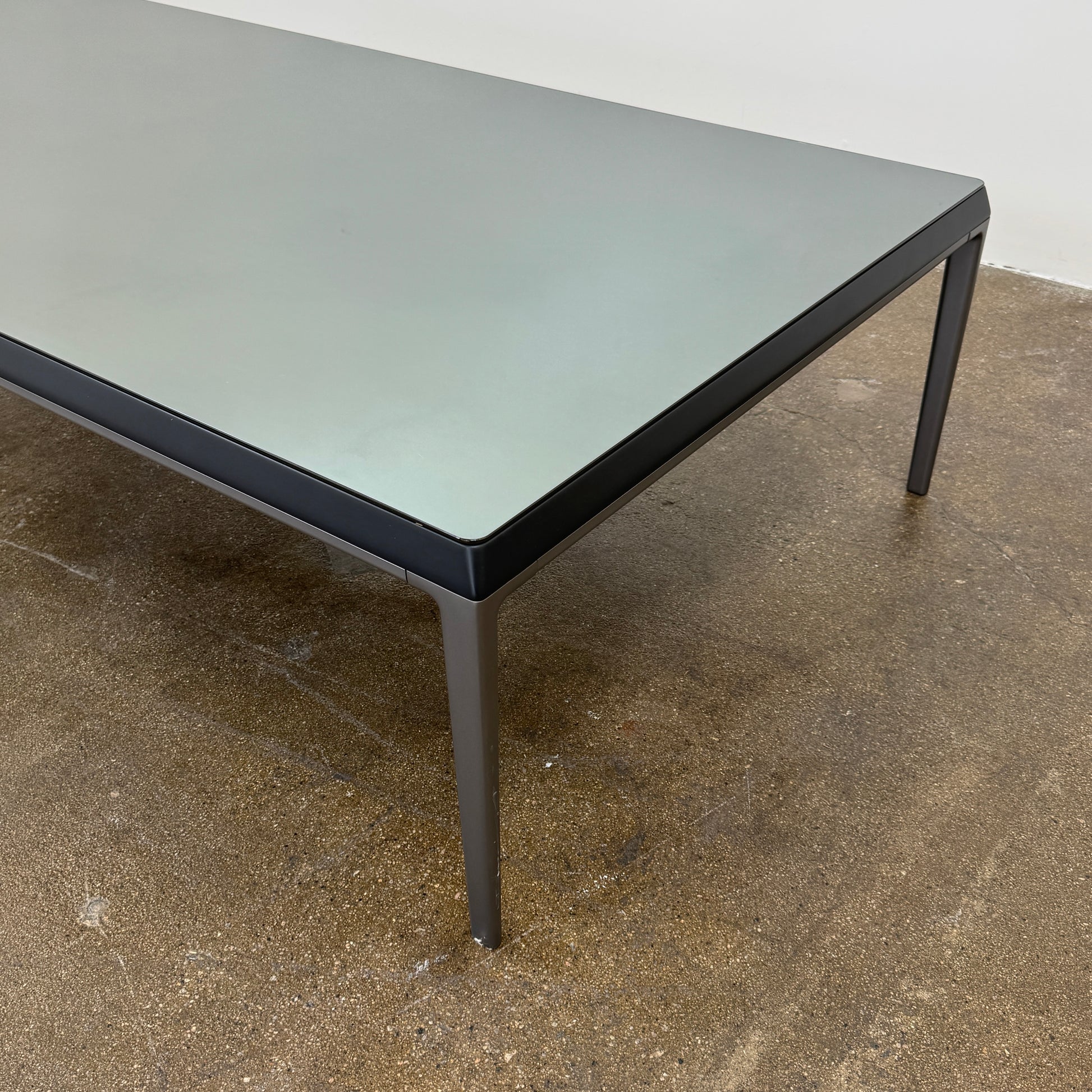 The B&B Italia Michel Coffee Table features a rectangular minimalist design with a flat gray surface and slim black metal legs, showcased against a plain white background.