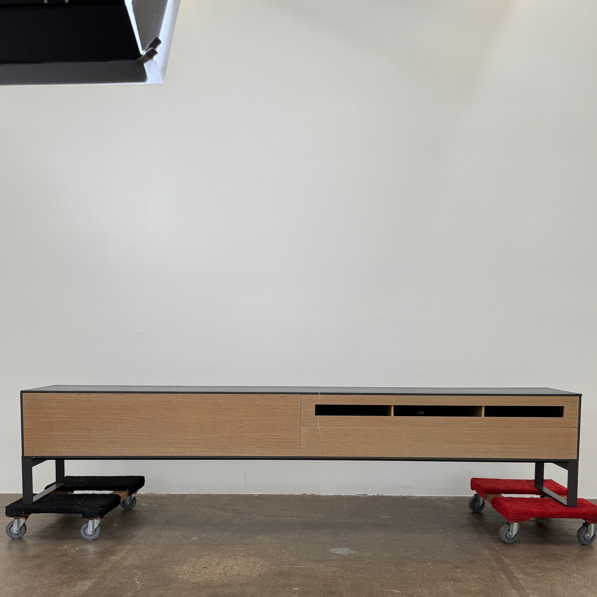 The Joan Lao Custom Media Console by Joan Lao is a black, modern low-profile piece made from sustainably sourced wood, featuring four drawers and open rectangular legs, shown against a plain white background.