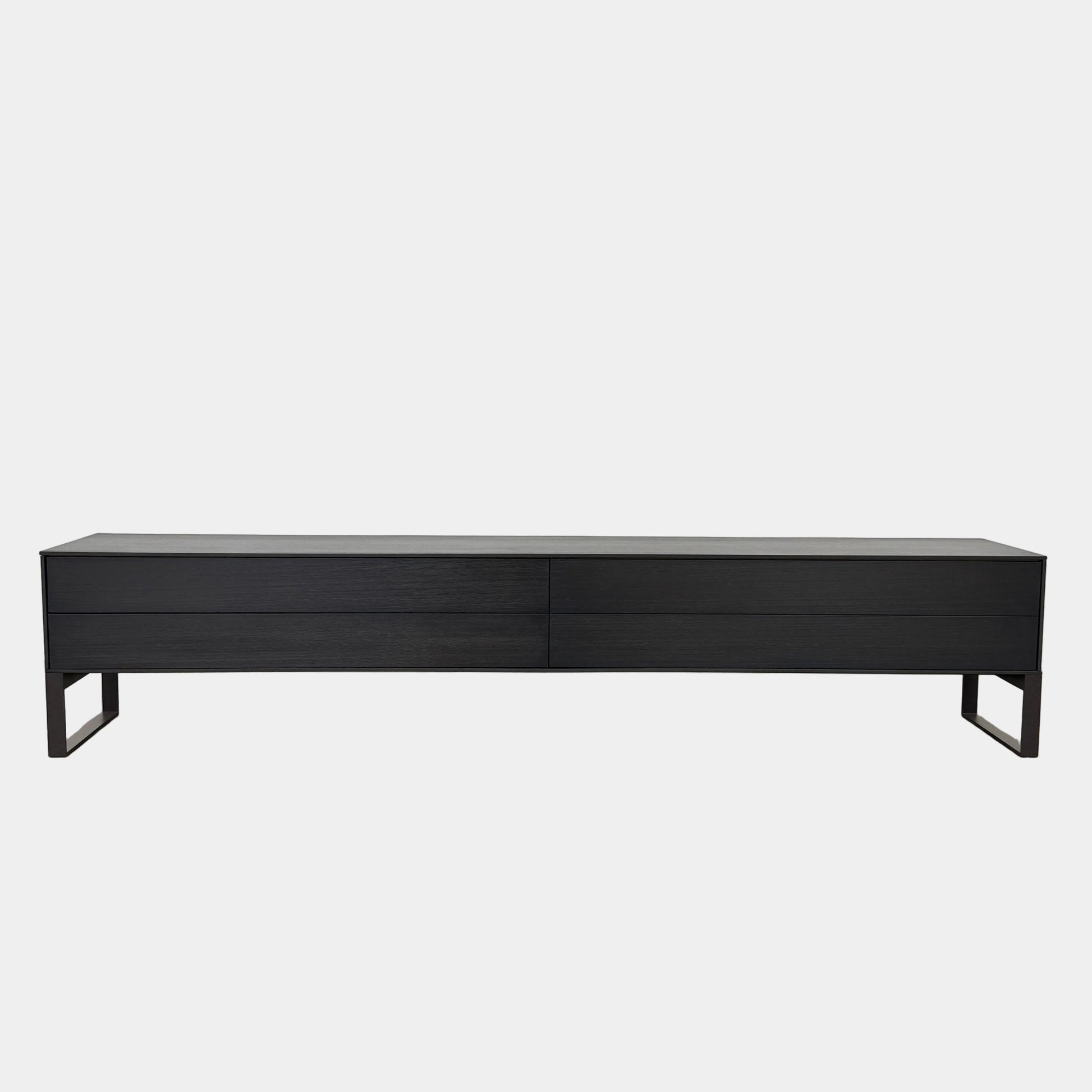 The Joan Lao Custom Media Console by Joan Lao is a black, modern low-profile piece made from sustainably sourced wood, featuring four drawers and open rectangular legs, shown against a plain white background.