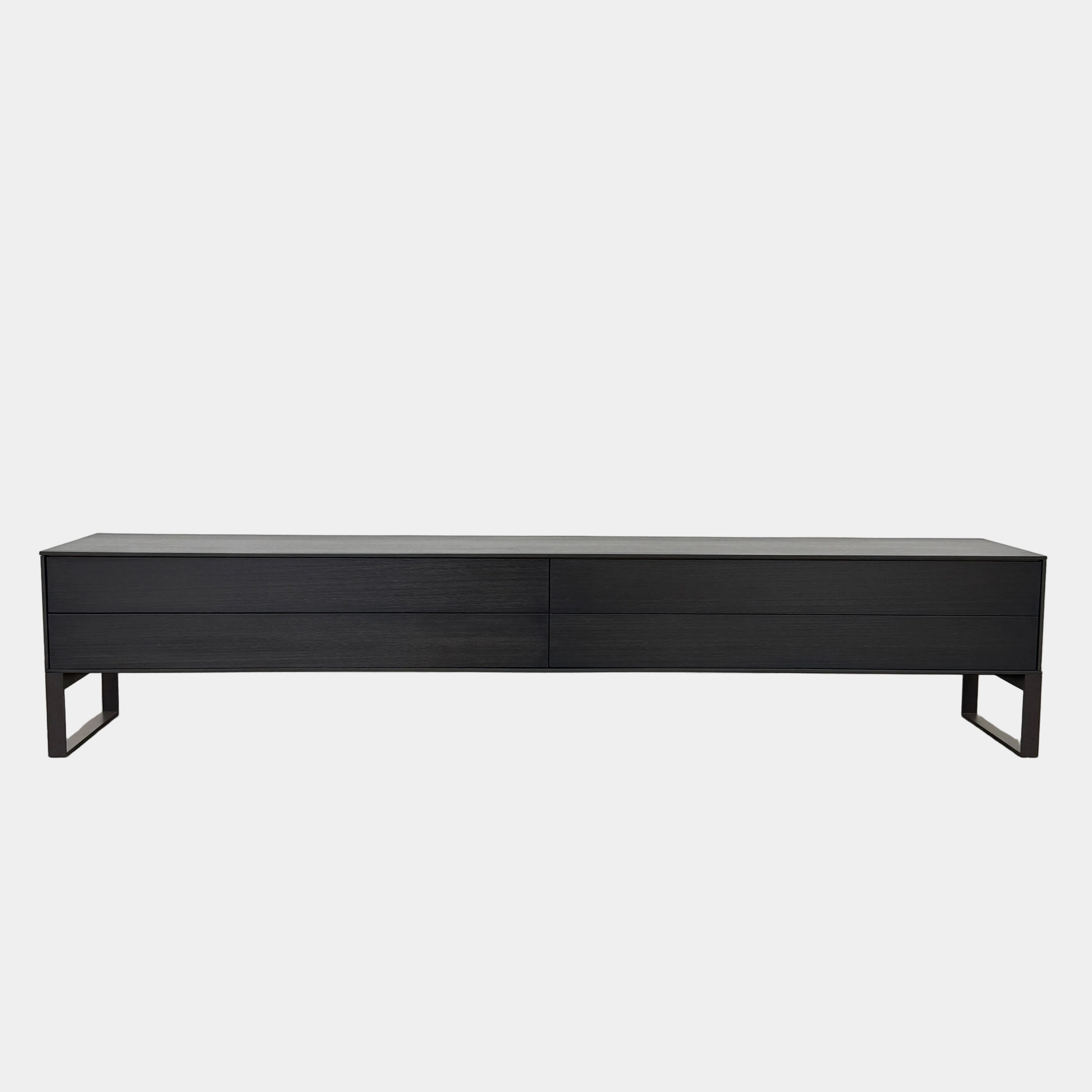 The Joan Lao Custom Media Console by Joan Lao is a black, modern low-profile piece made from sustainably sourced wood, featuring four drawers and open rectangular legs, shown against a plain white background.
