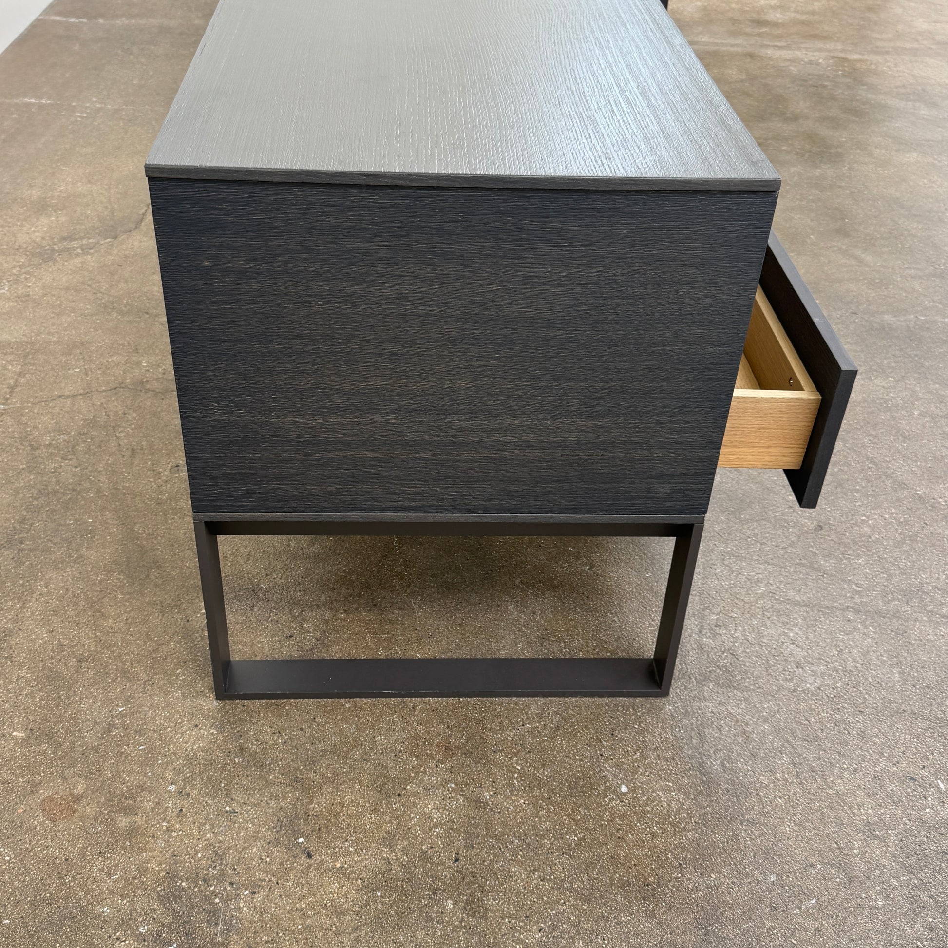 The Joan Lao Custom Media Console by Joan Lao is a black, modern low-profile piece made from sustainably sourced wood, featuring four drawers and open rectangular legs, shown against a plain white background.