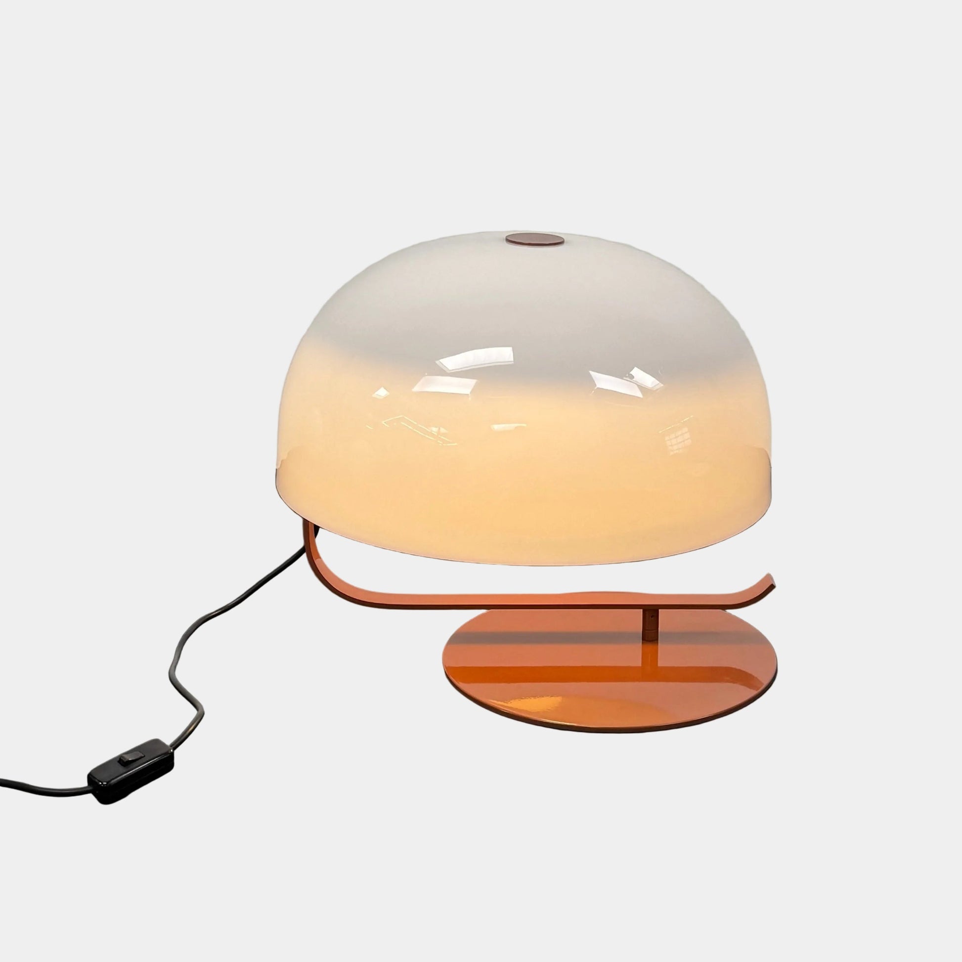 The Oluce Zanuso 275 Table Light by Oluce is a modern lamp inspired by Italian design, with a white domed glass shade, orange base, and black power cord with switch, shown against a plain background.