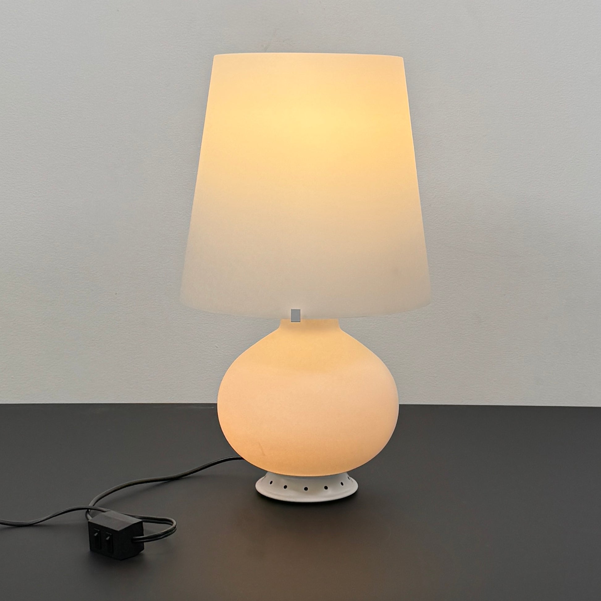 The Fontana Arte Table Lamp - Medium by Fontana Arte features a modernist design with a round base and wide, tapered lampshade, displayed against a plain light background.