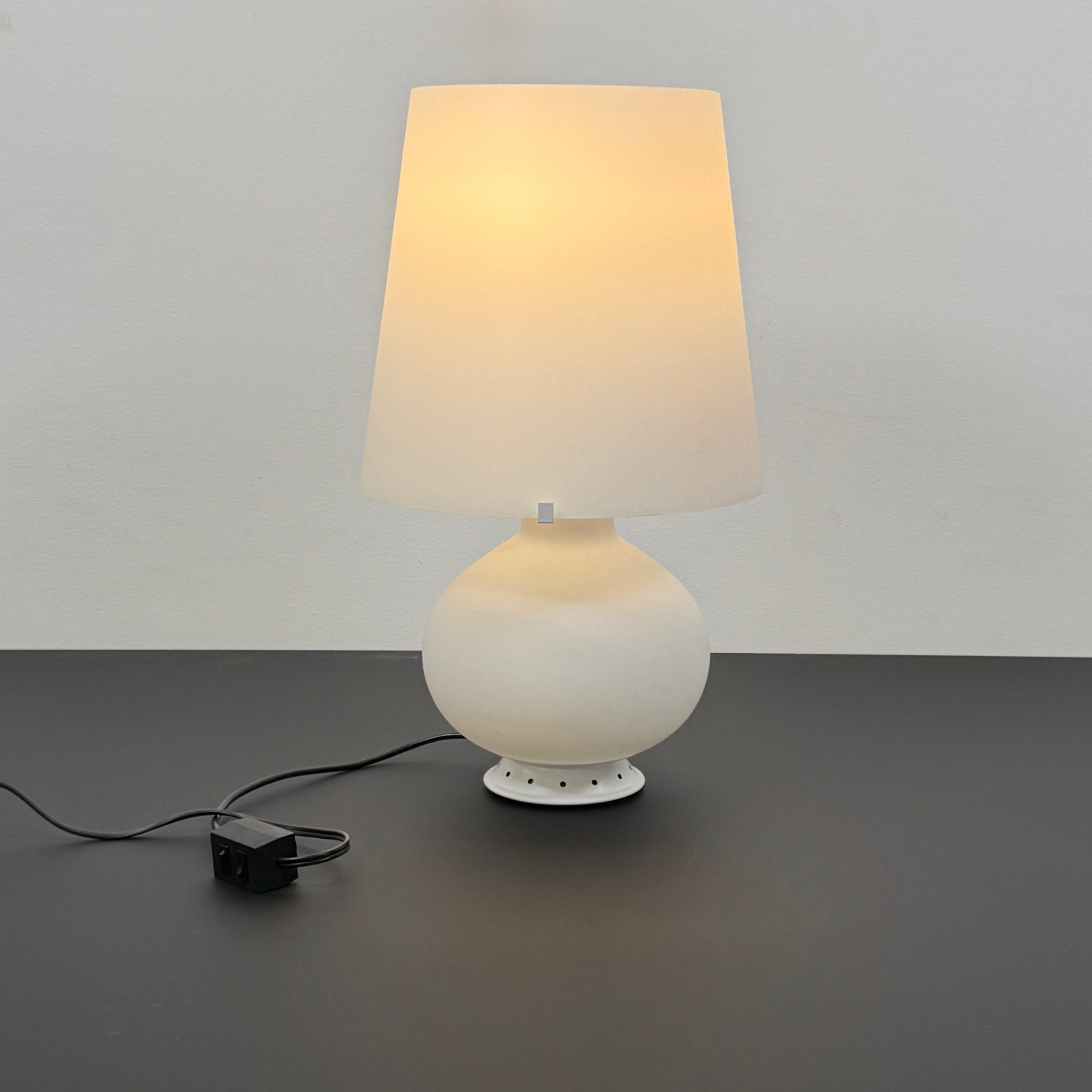 The Fontana Arte Table Lamp - Medium by Fontana Arte features a modernist design with a round base and wide, tapered lampshade, displayed against a plain light background.