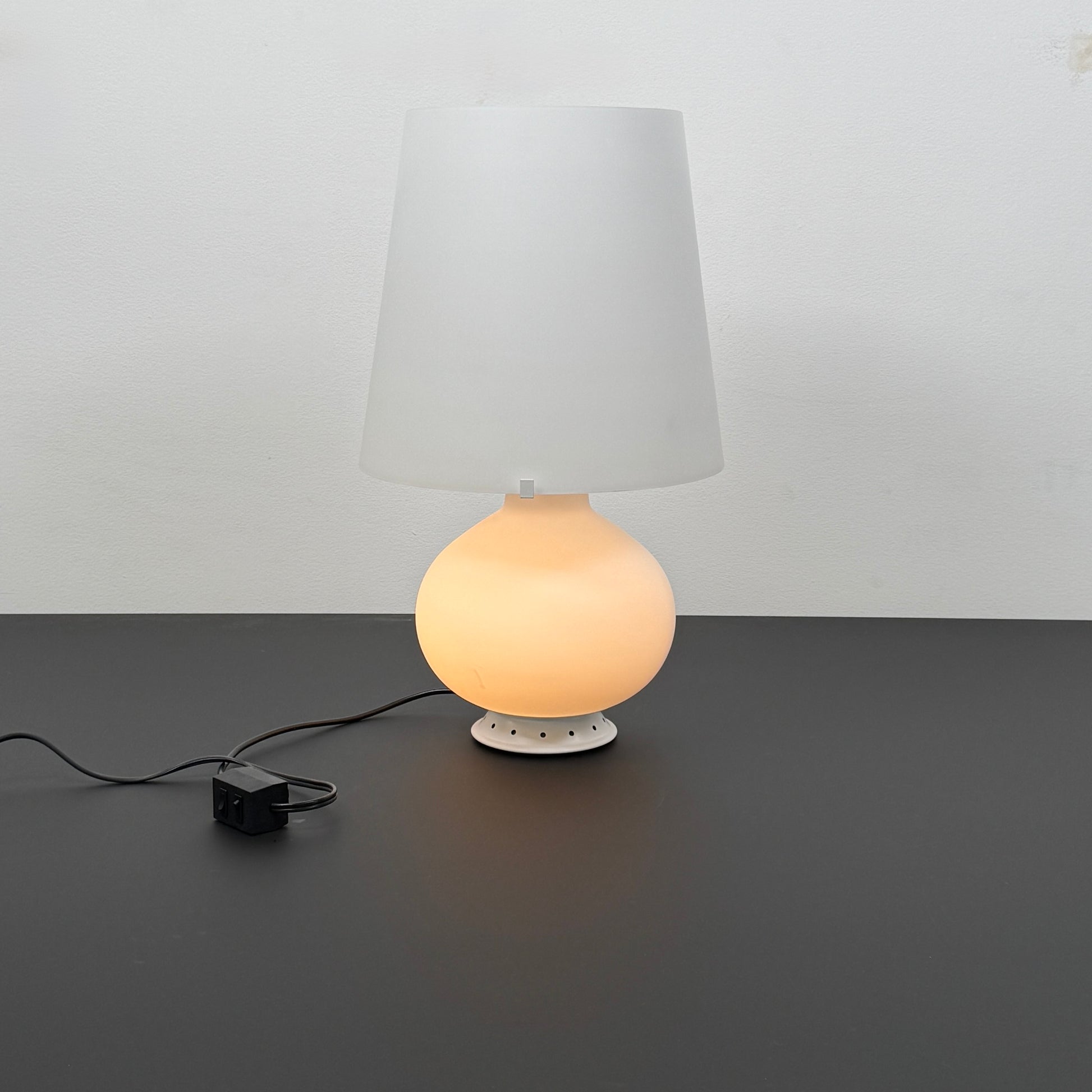 The Fontana Arte Table Lamp - Medium by Fontana Arte features a modernist design with a round base and wide, tapered lampshade, displayed against a plain light background.