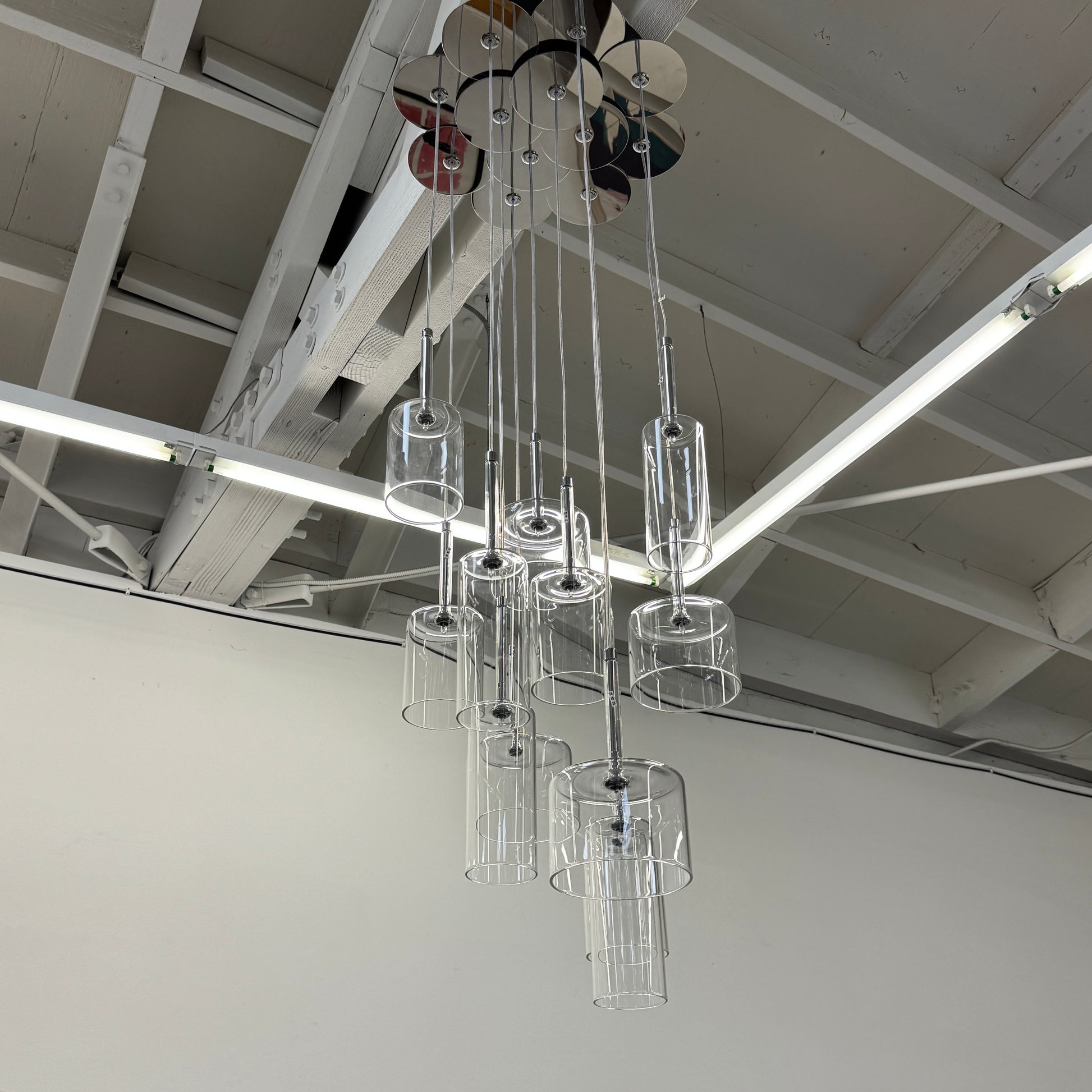 The AXO Light Axolight 12 Light Spillray Suspension Light features modern cylindrical glass pendants on black cords from a round ceiling mount, ideal for contemporary lighting schemes.