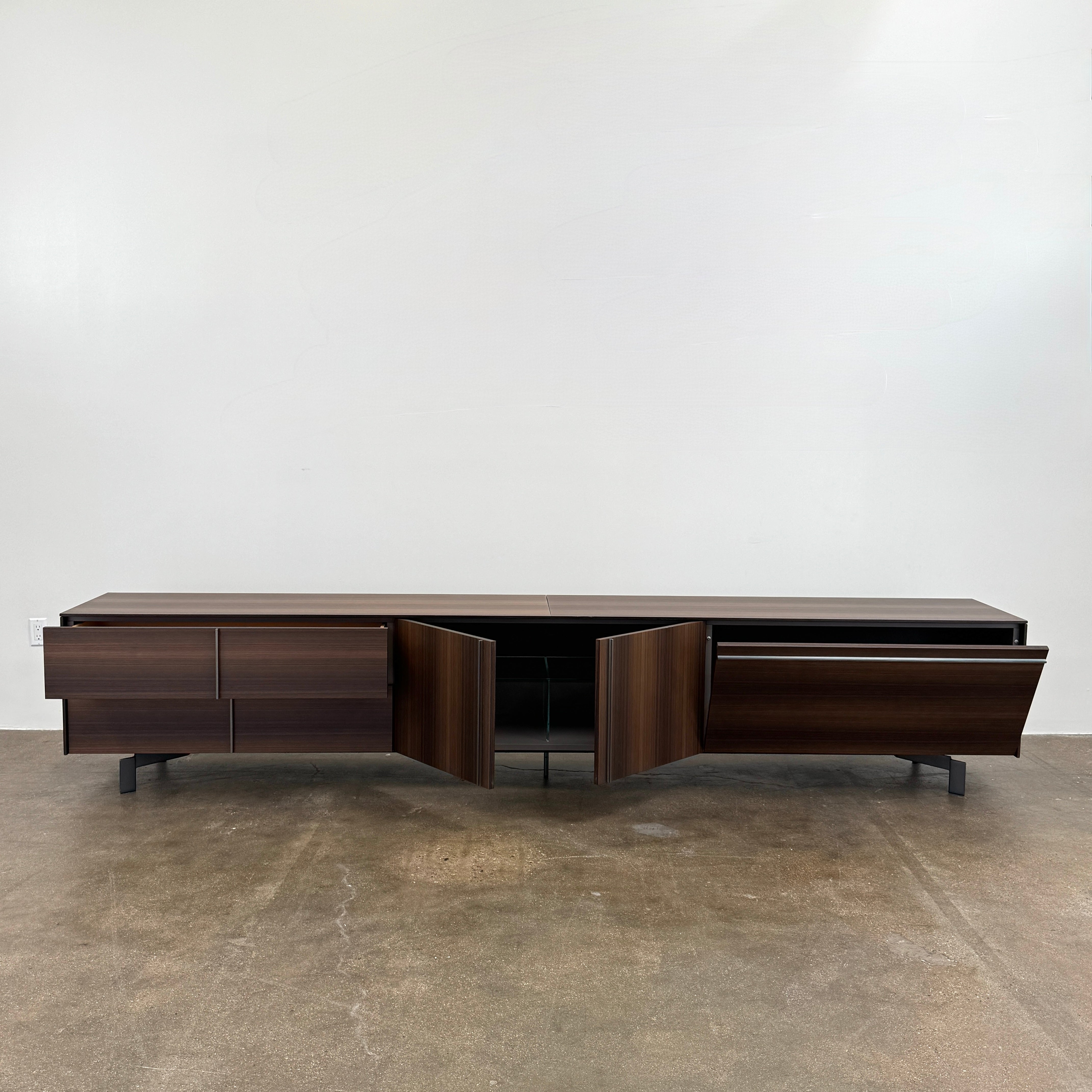 The Molteni & C Pass-word Console by Molteni & C is a modern, low-profile Eucalyptus wood sideboard with two drawers, cabinets on each side, and black metal legs, shown against a plain white background.