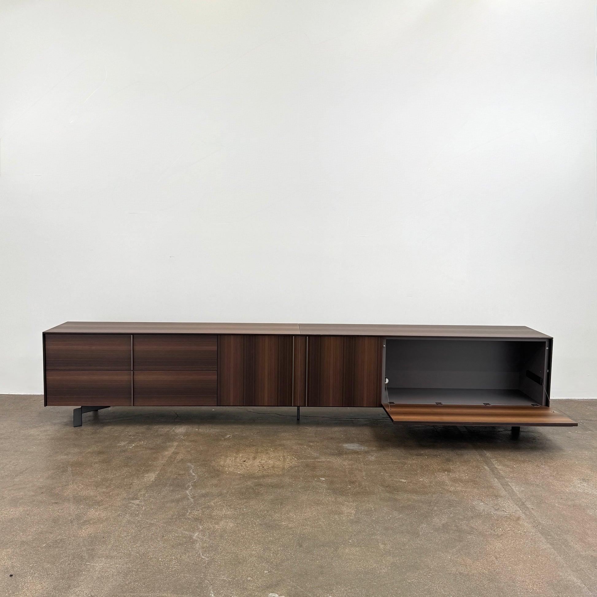 The Molteni & C Pass-word Console by Molteni & C is a modern, low-profile Eucalyptus wood sideboard with two drawers, cabinets on each side, and black metal legs, shown against a plain white background.