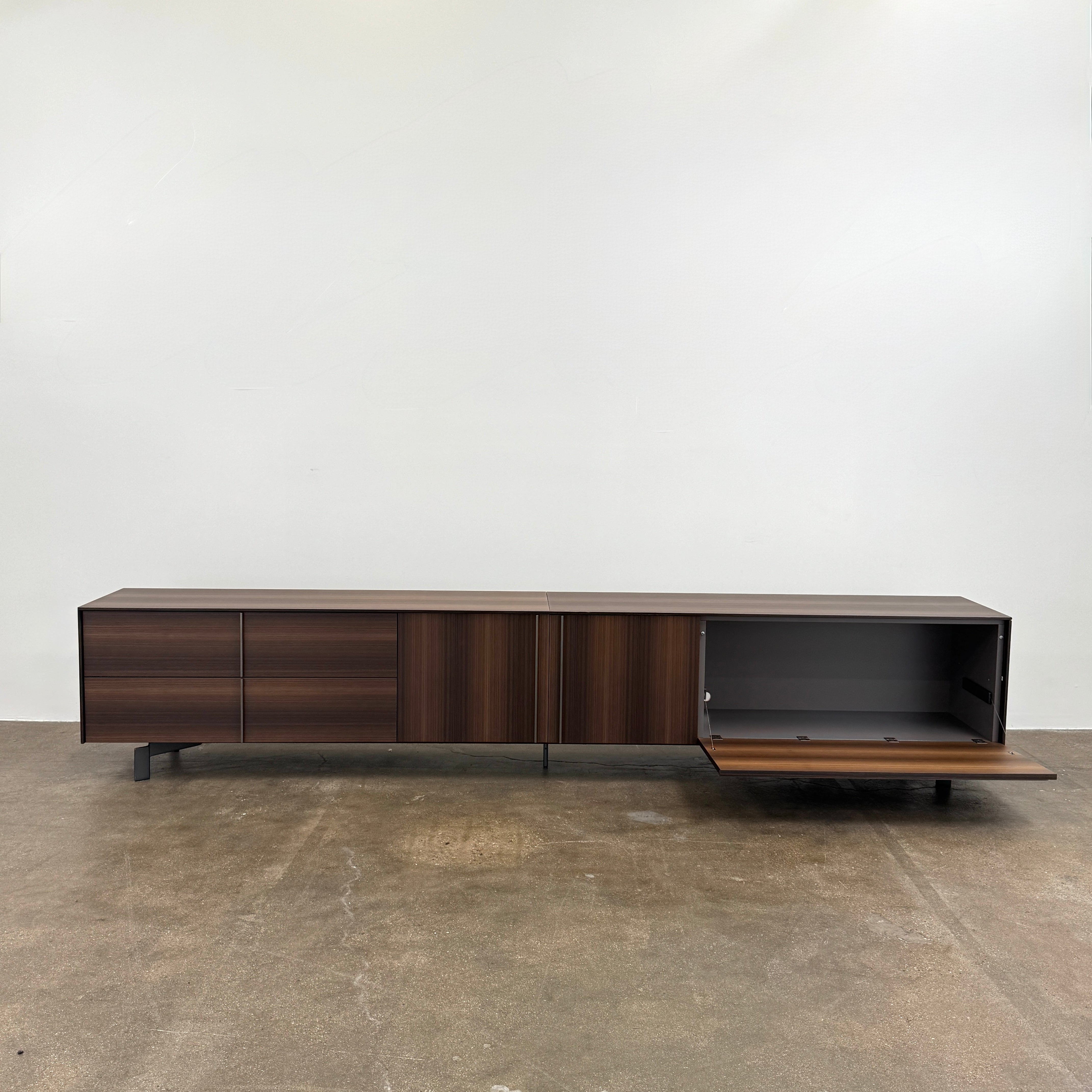 The Molteni & C Pass-word Console by Molteni & C is a modern, low-profile Eucalyptus wood sideboard with two drawers, cabinets on each side, and black metal legs, shown against a plain white background.