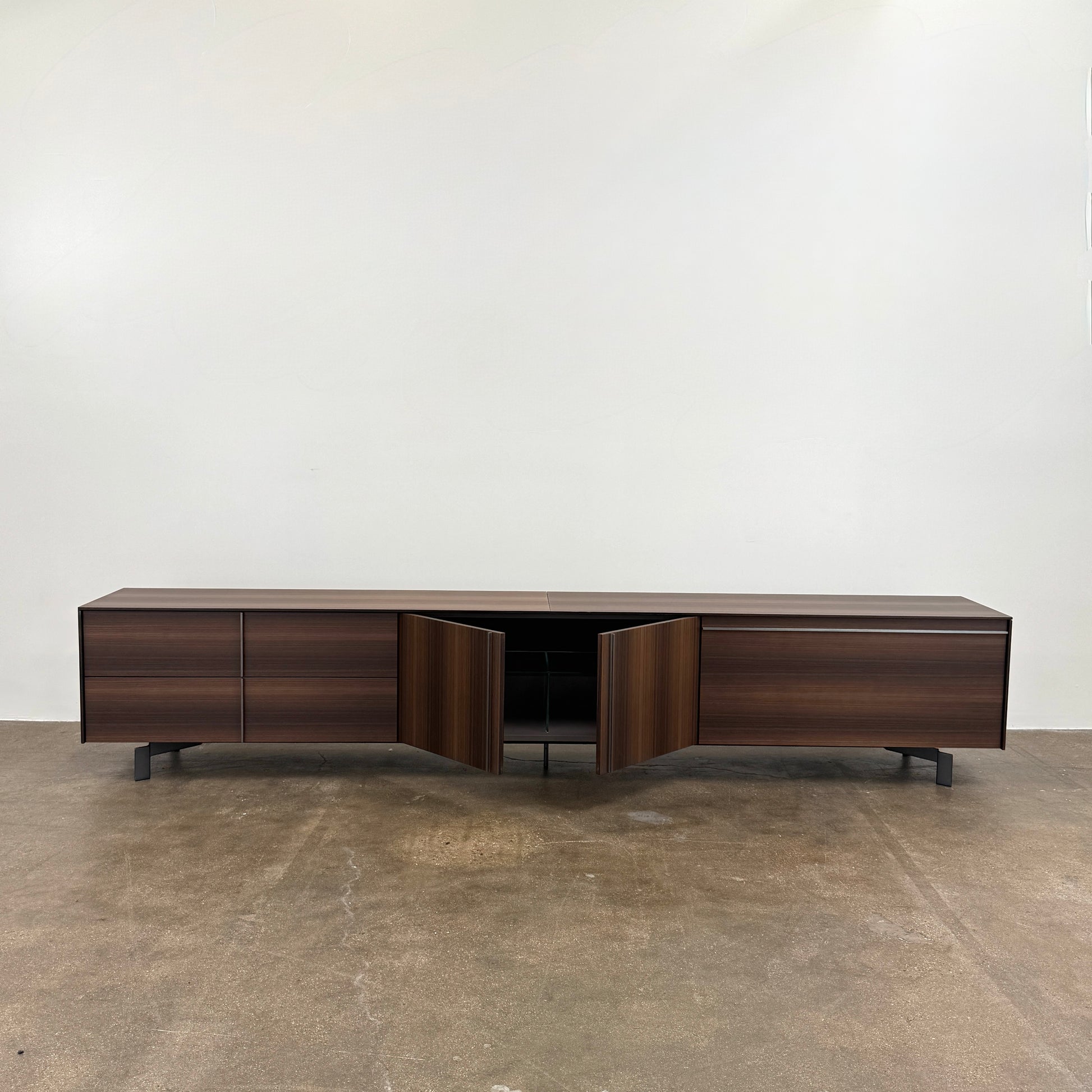 The Molteni & C Pass-word Console by Molteni & C is a modern, low-profile Eucalyptus wood sideboard with two drawers, cabinets on each side, and black metal legs, shown against a plain white background.