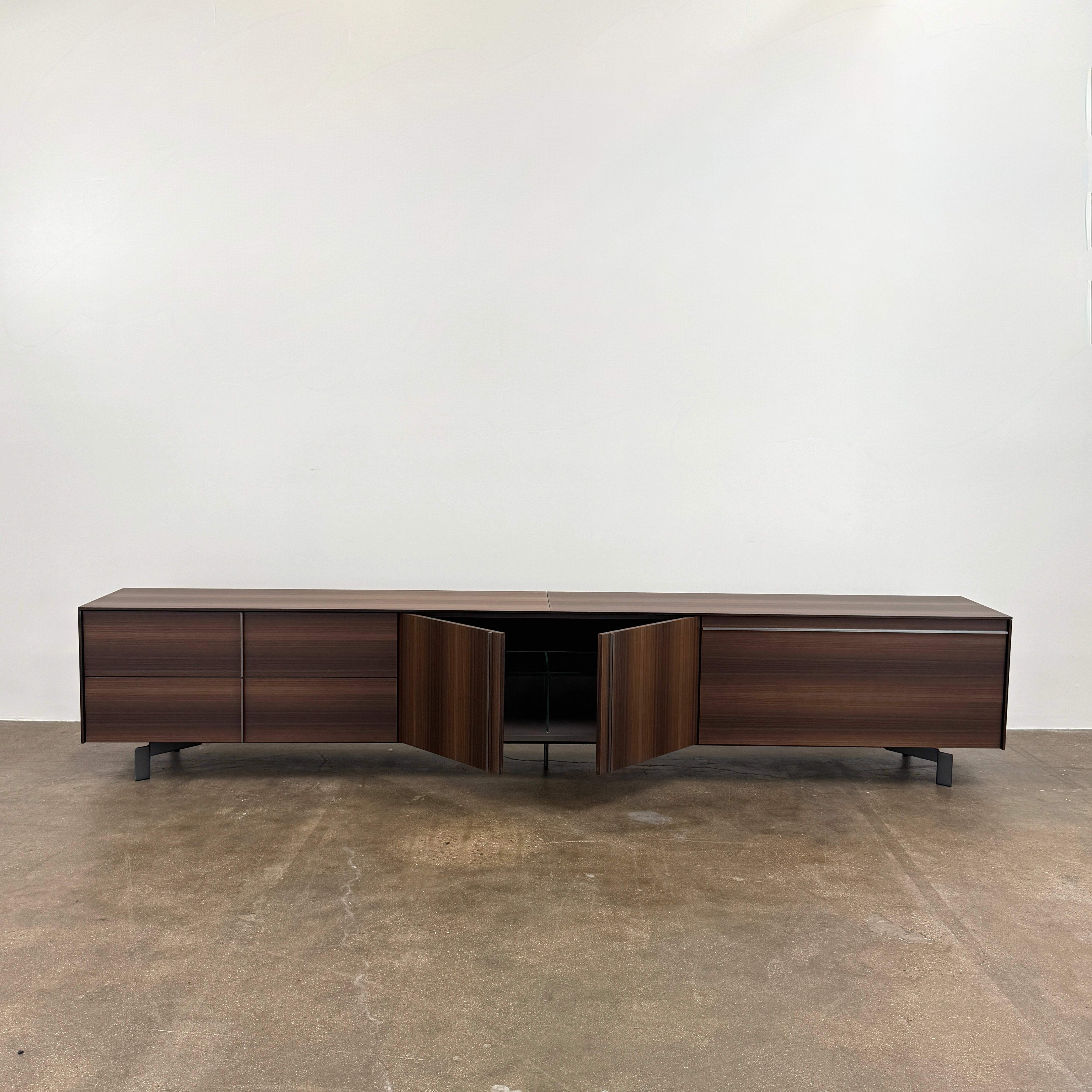 The Molteni & C Pass-word Console by Molteni & C is a modern, low-profile Eucalyptus wood sideboard with two drawers, cabinets on each side, and black metal legs, shown against a plain white background.
