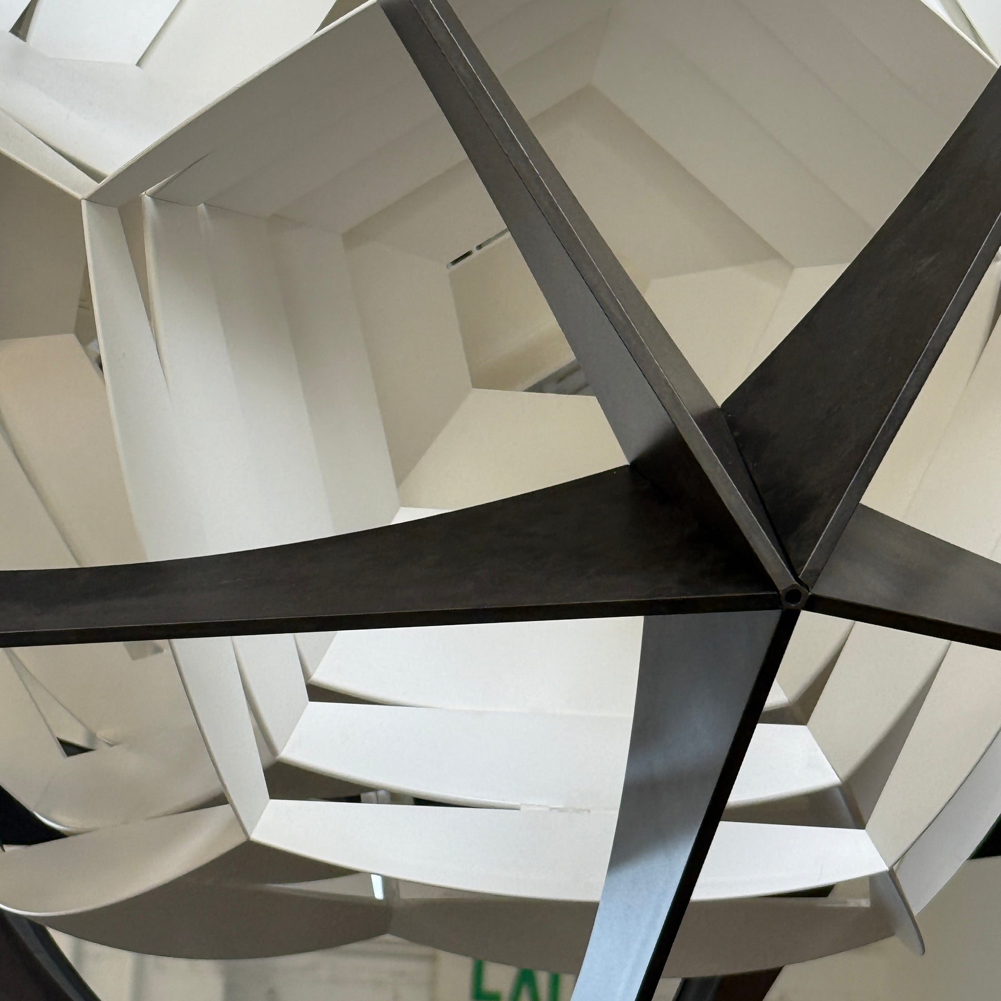 The Louis Poulsen OE Quasi Pendant is a sculptural geometric light fixture featuring a black outer frame and layered white panels, elegantly suspended by a cord—a modern design by Louis Poulsen.