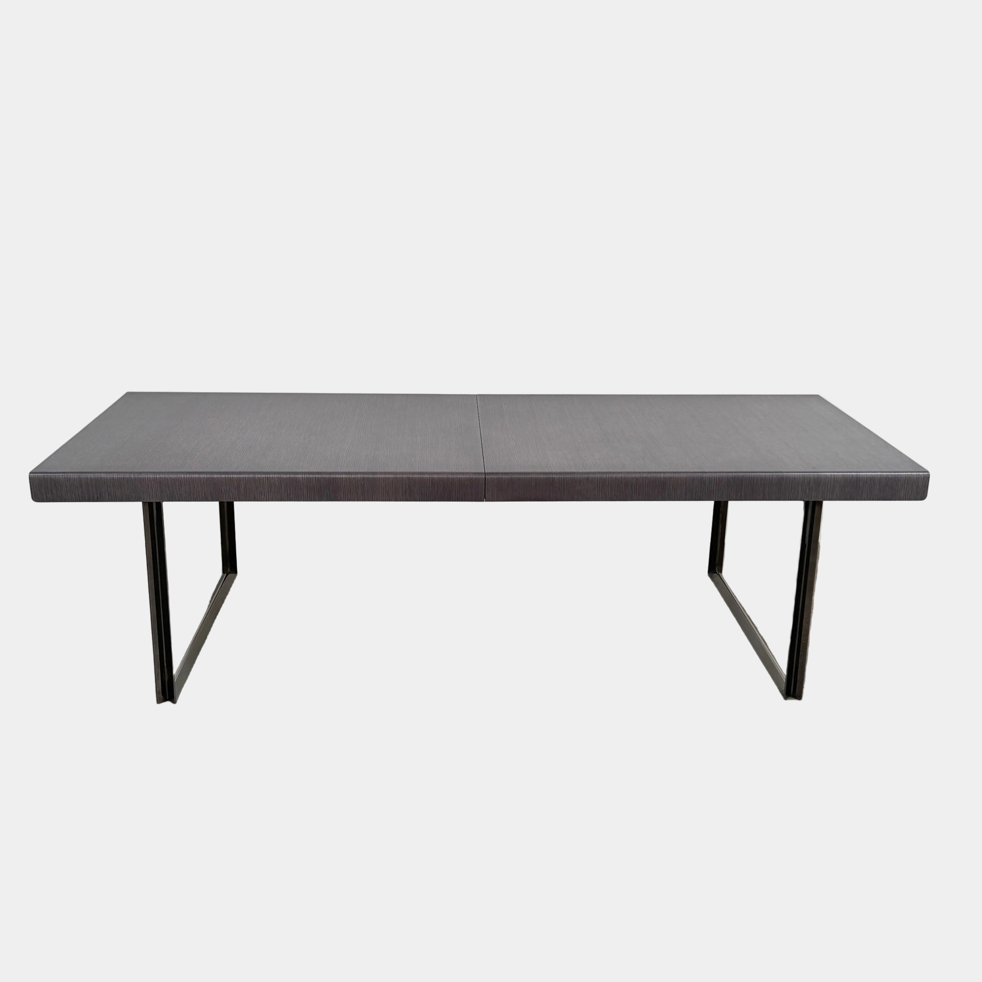 The B&B Italia Athos 12 Extendable Dining Table by Paolo Piva features a sleek rectangular dark gray top and black metal legs, showcased against a plain white background.