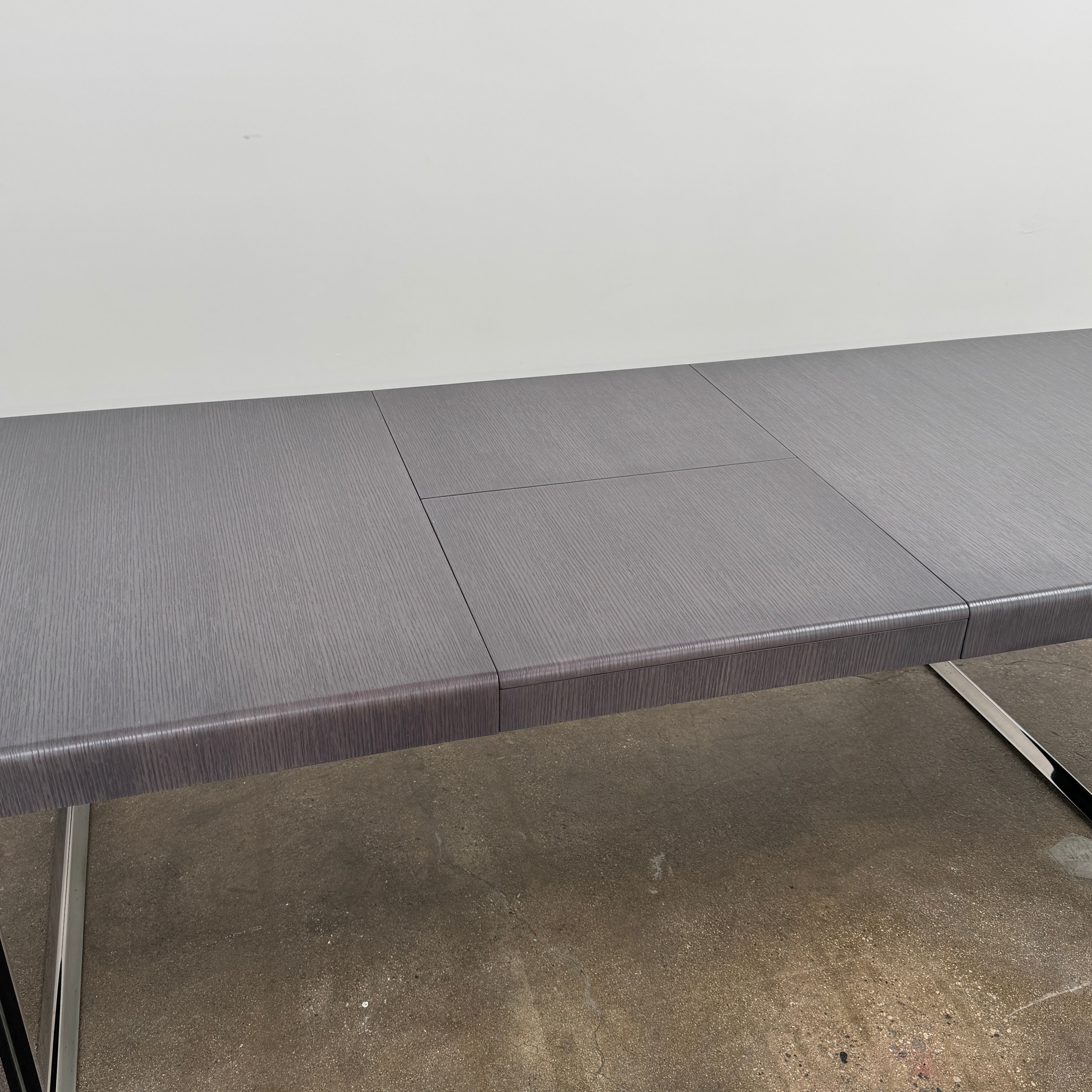 The B&B Italia Athos 12 Extendable Dining Table by Paolo Piva features a sleek rectangular dark gray top and black metal legs, showcased against a plain white background.