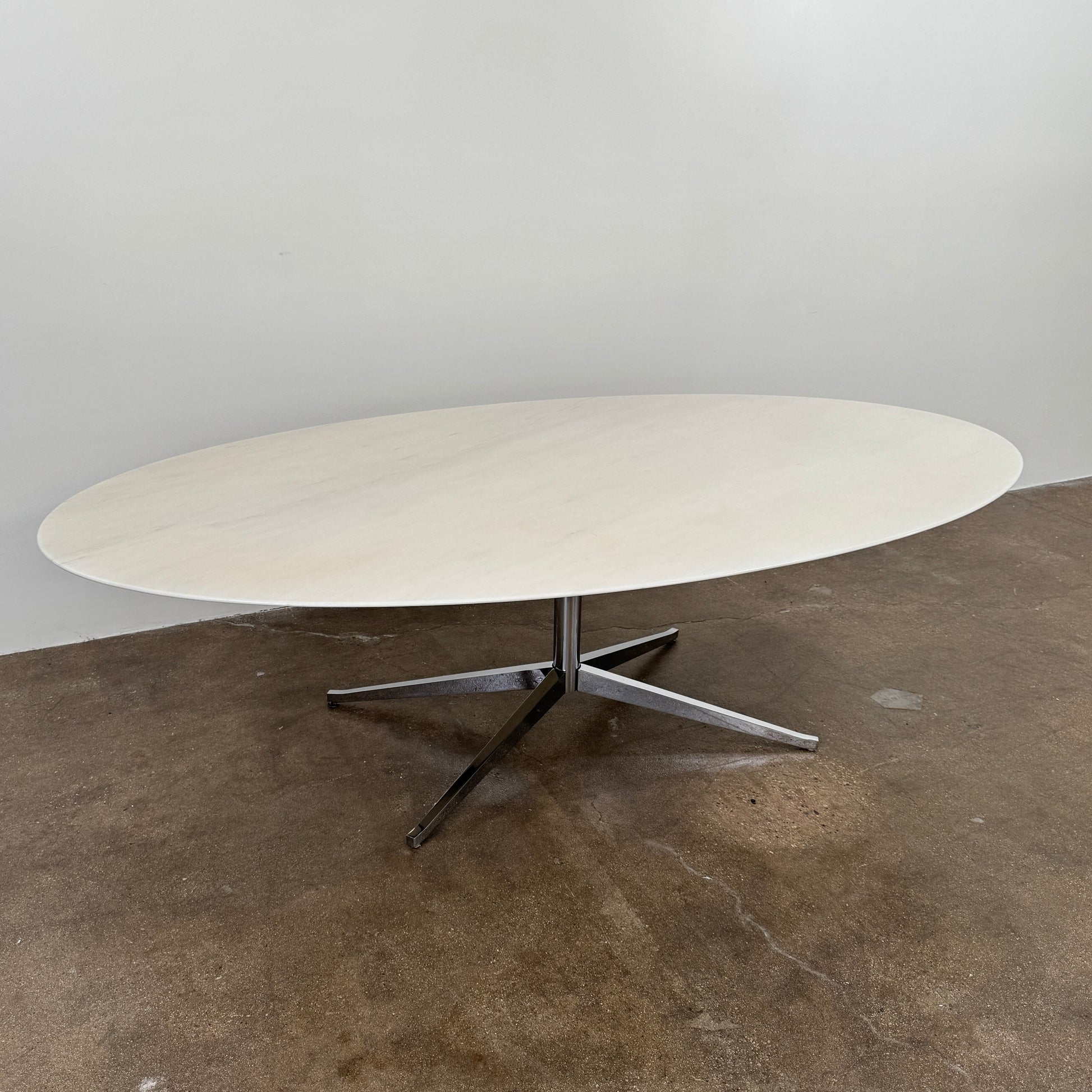Florence Knoll’s DWR Florence Knoll Oval White Statuarietto Marble "Table Desk" features a slim marble top and black four-legged base, inspired by the iconic design, displayed against a plain white background.