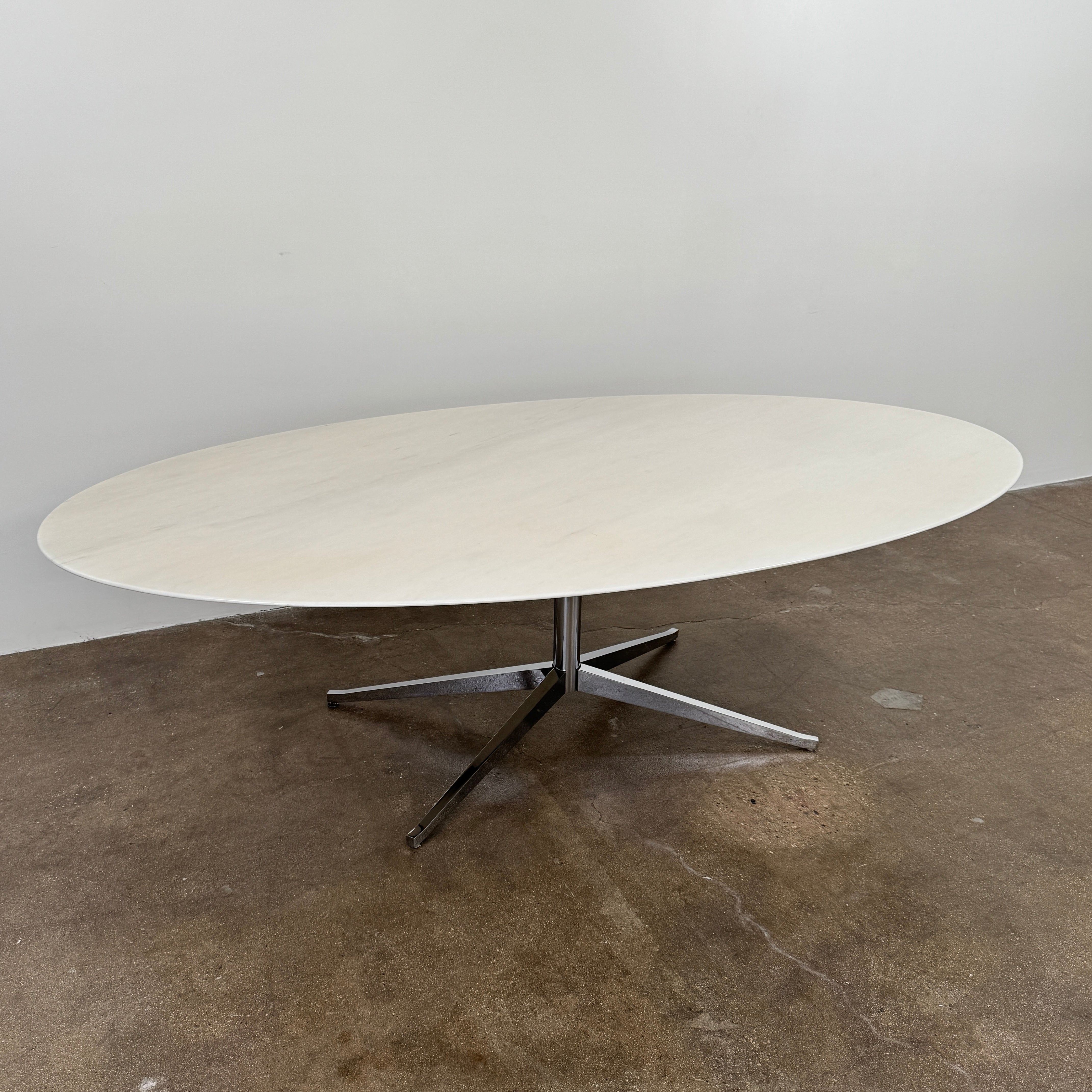Florence Knoll’s DWR Florence Knoll Oval White Statuarietto Marble "Table Desk" features a slim marble top and black four-legged base, inspired by the iconic design, displayed against a plain white background.
