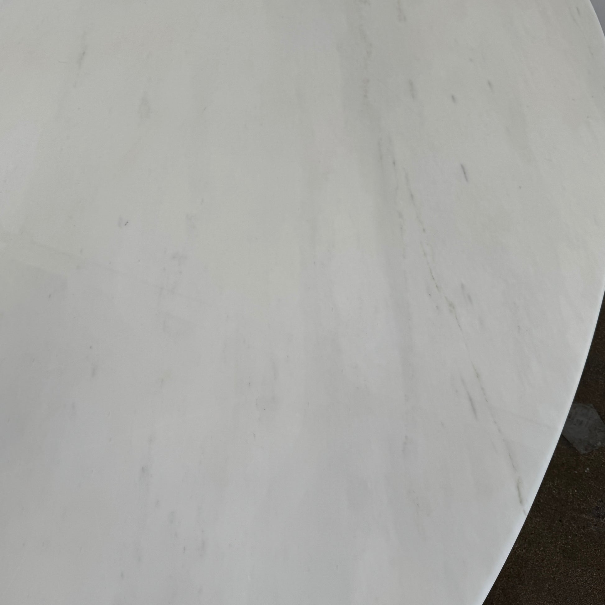 Florence Knoll’s DWR Florence Knoll Oval White Statuarietto Marble "Table Desk" features a slim marble top and black four-legged base, inspired by the iconic design, displayed against a plain white background.