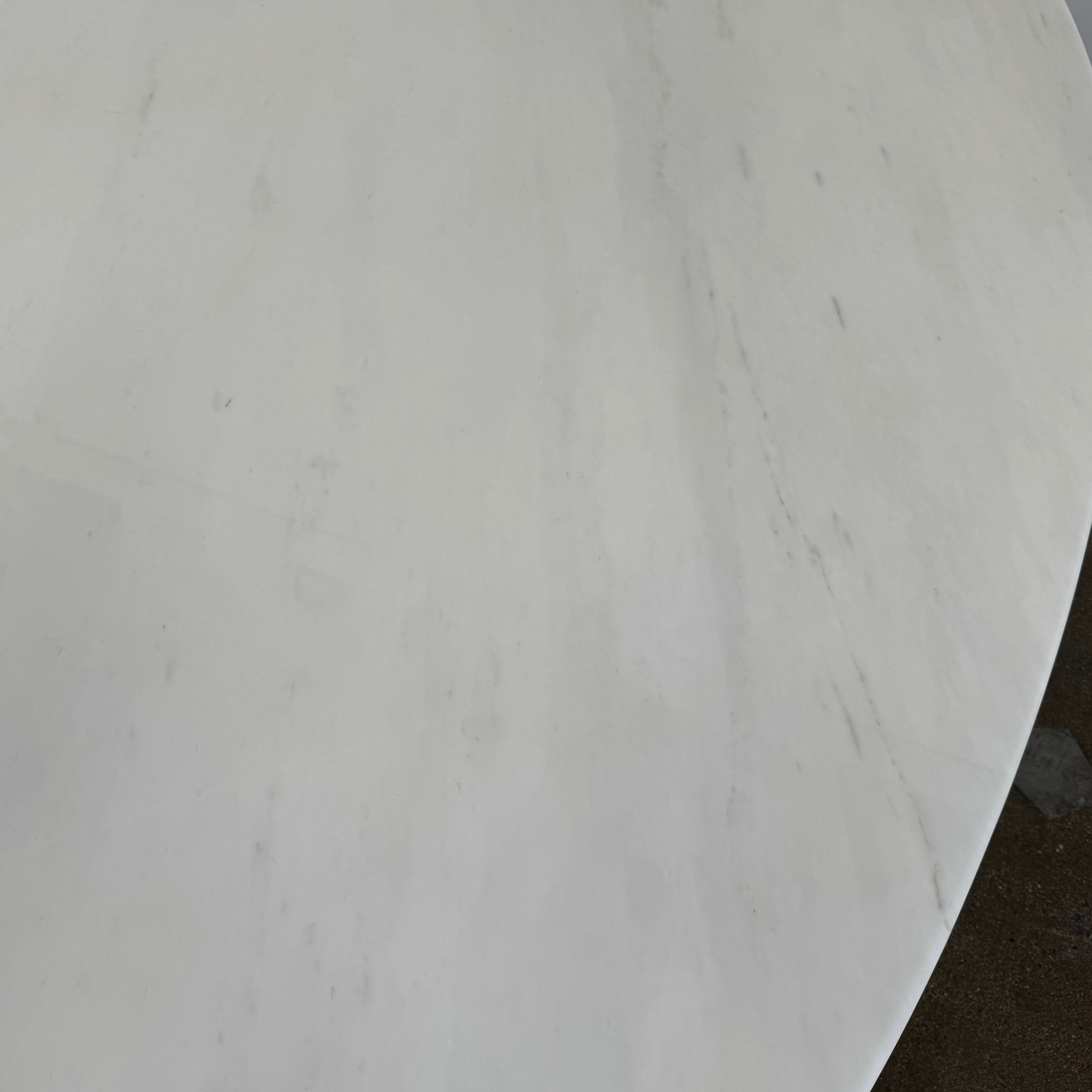 Florence Knoll’s DWR Florence Knoll Oval White Statuarietto Marble "Table Desk" features a slim marble top and black four-legged base, inspired by the iconic design, displayed against a plain white background.