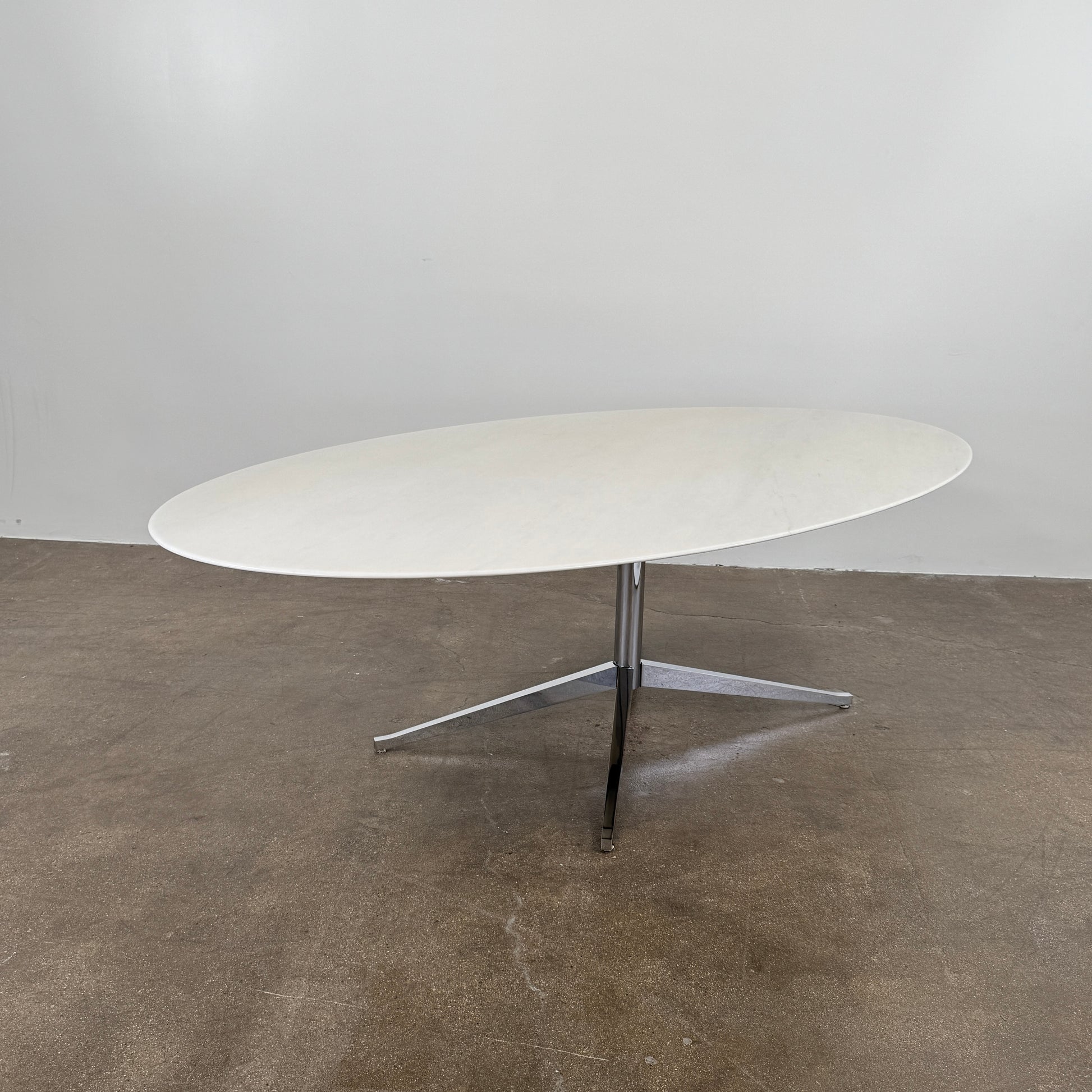 Florence Knoll’s DWR Florence Knoll Oval White Statuarietto Marble "Table Desk" features a slim marble top and black four-legged base, inspired by the iconic design, displayed against a plain white background.