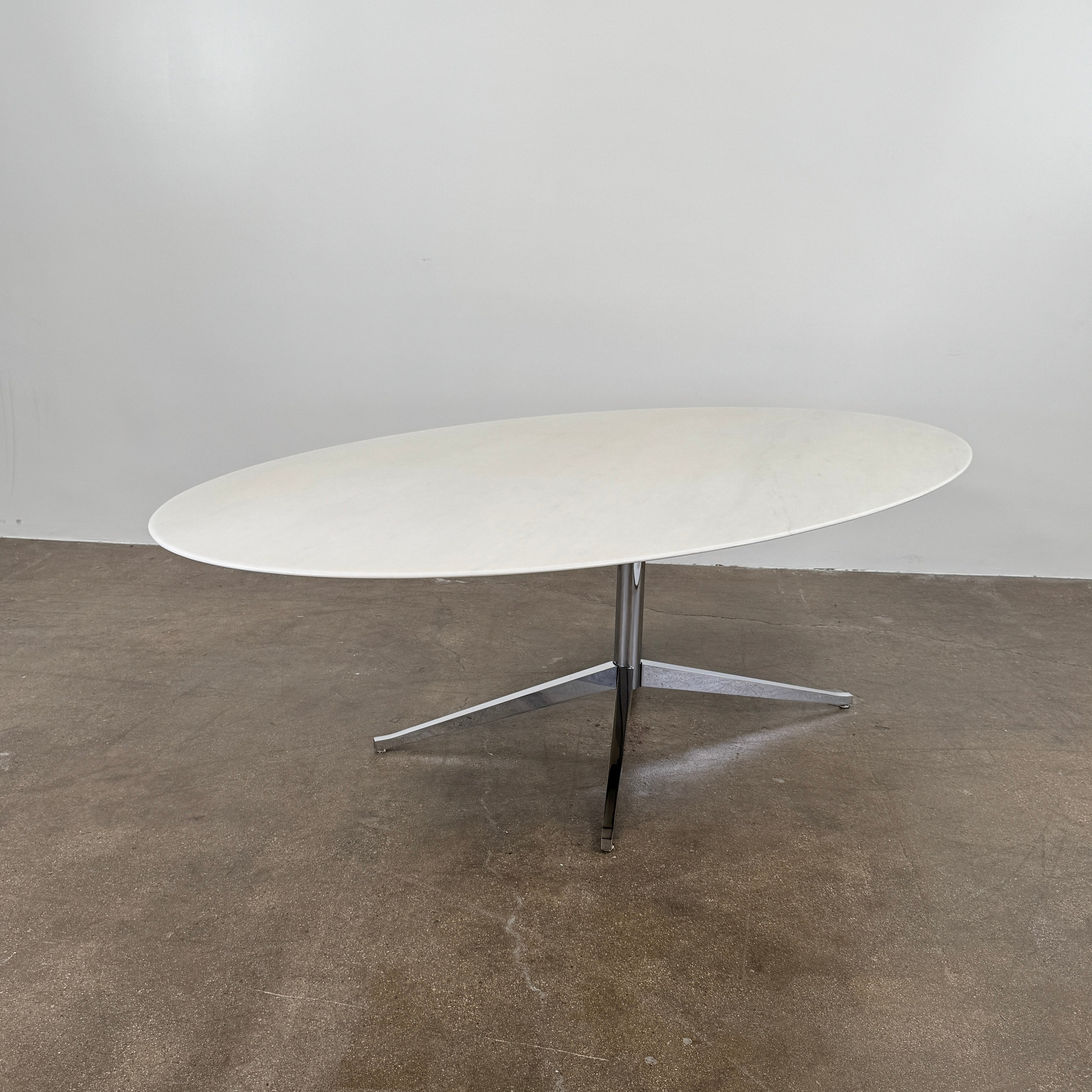 Florence Knoll’s DWR Florence Knoll Oval White Statuarietto Marble "Table Desk" features a slim marble top and black four-legged base, inspired by the iconic design, displayed against a plain white background.