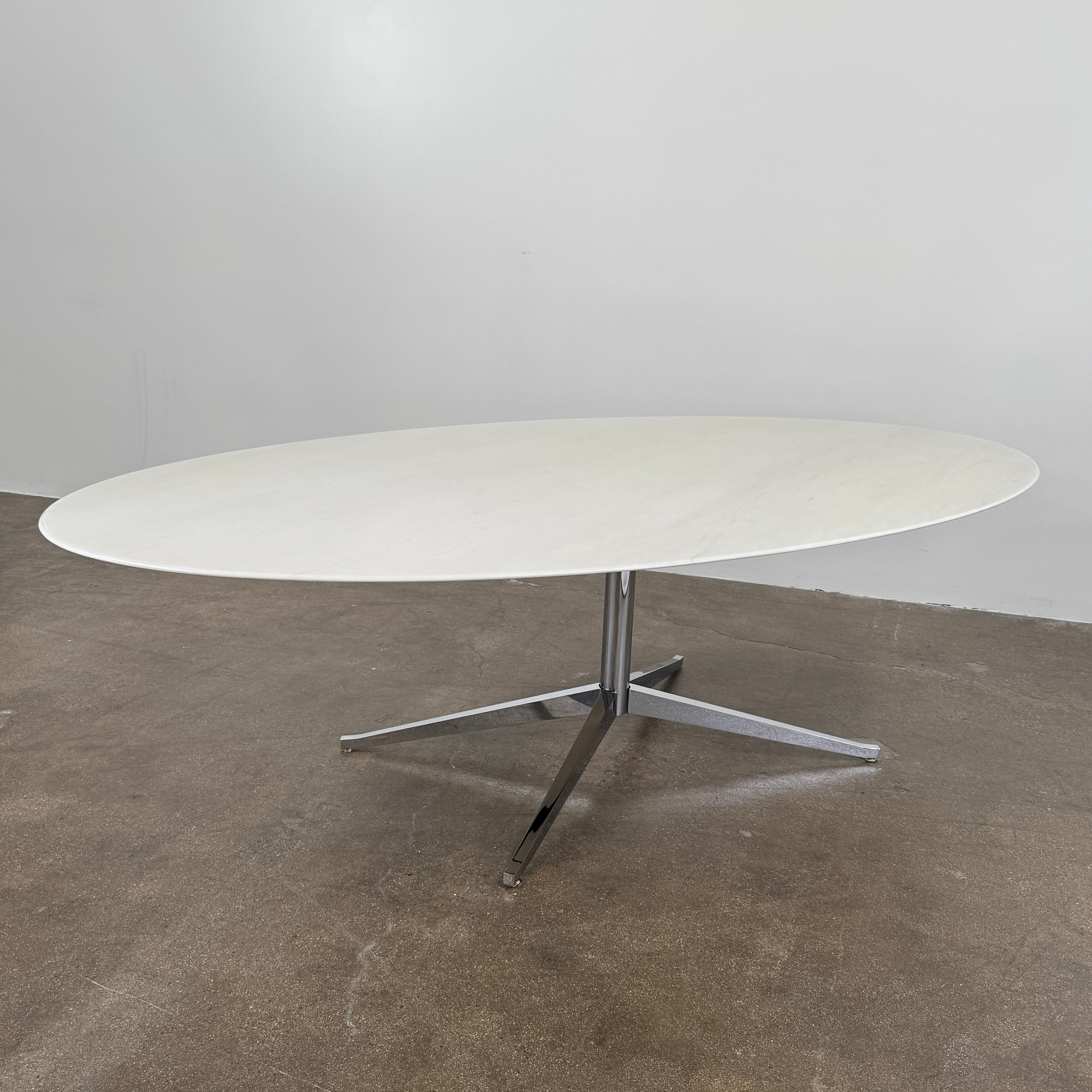 Florence Knoll’s DWR Florence Knoll Oval White Statuarietto Marble "Table Desk" features a slim marble top and black four-legged base, inspired by the iconic design, displayed against a plain white background.