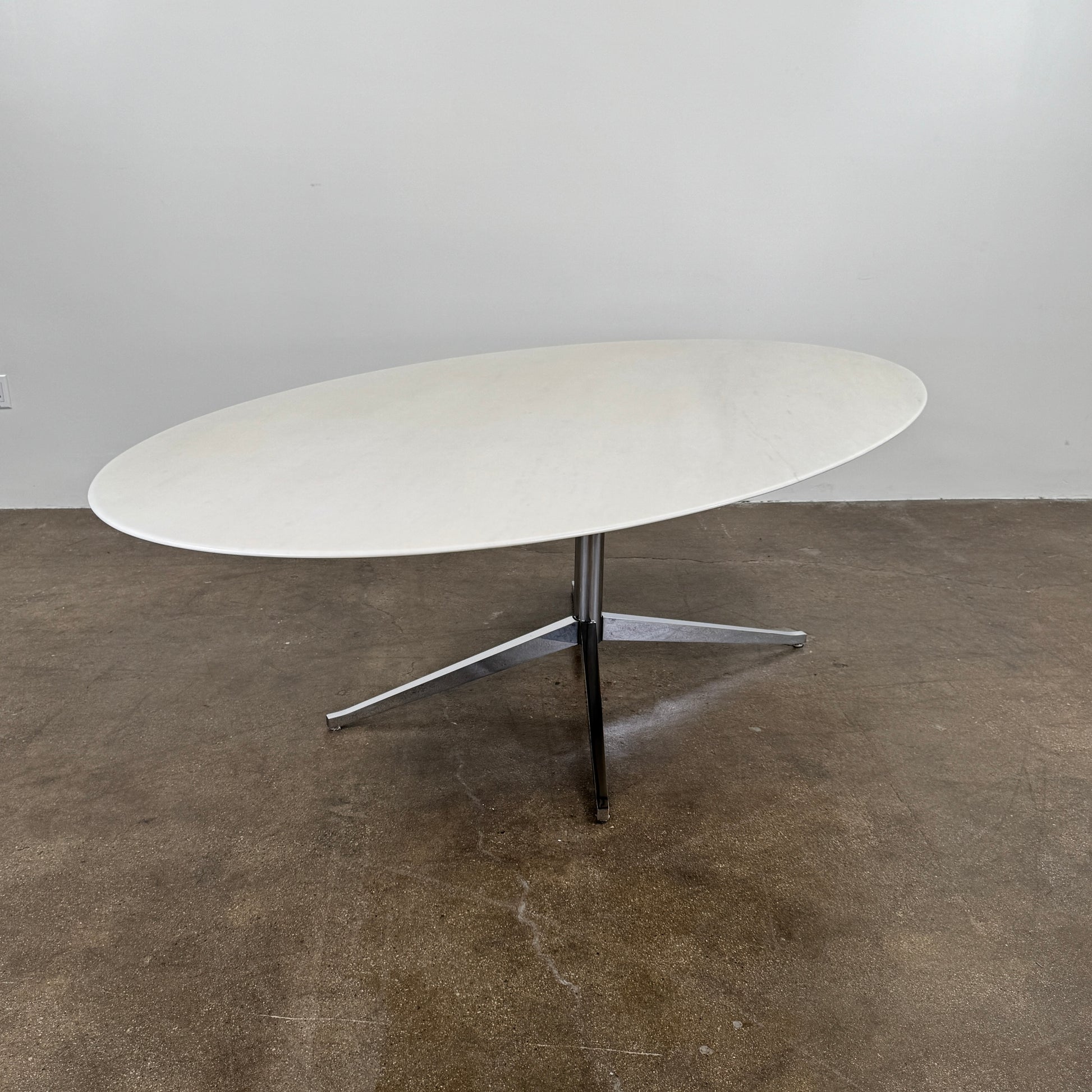 Florence Knoll’s DWR Florence Knoll Oval White Statuarietto Marble "Table Desk" features a slim marble top and black four-legged base, inspired by the iconic design, displayed against a plain white background.