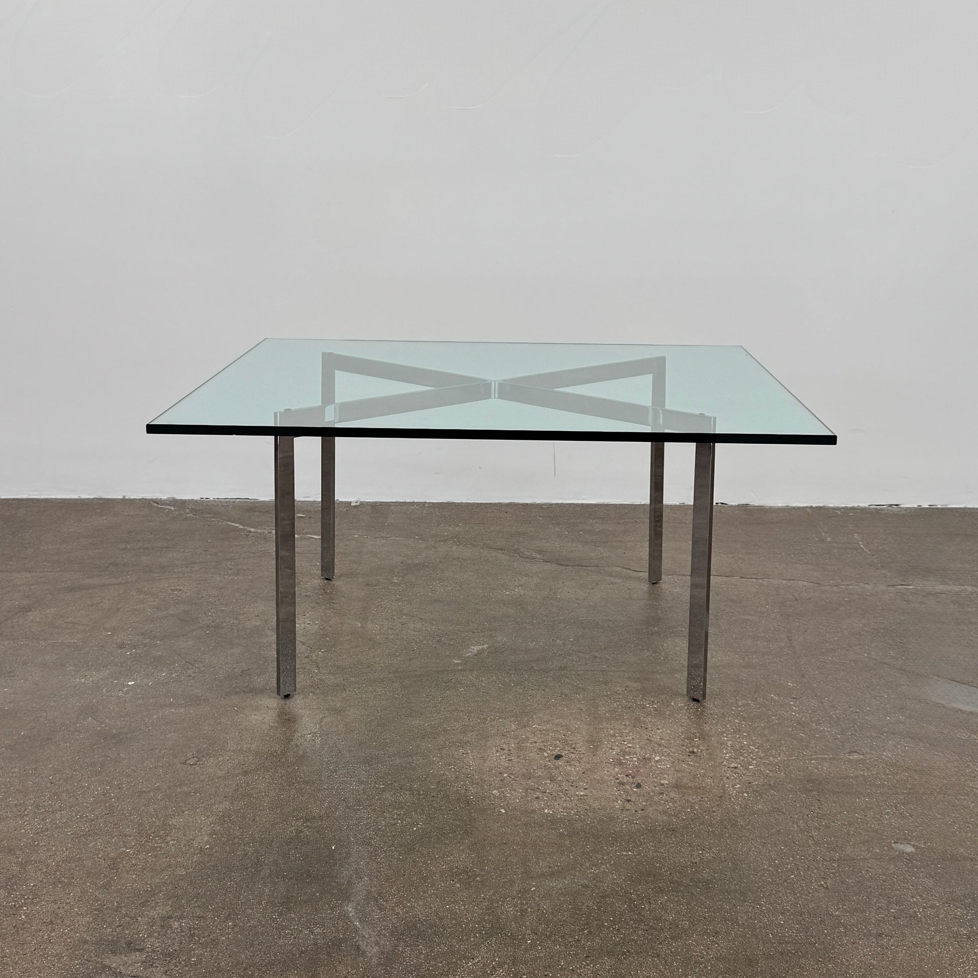 The Vintage DWR Barcelona Coffee Table by DWR features a rectangular glass top, four metal legs, and a visible metal support frame underneath.