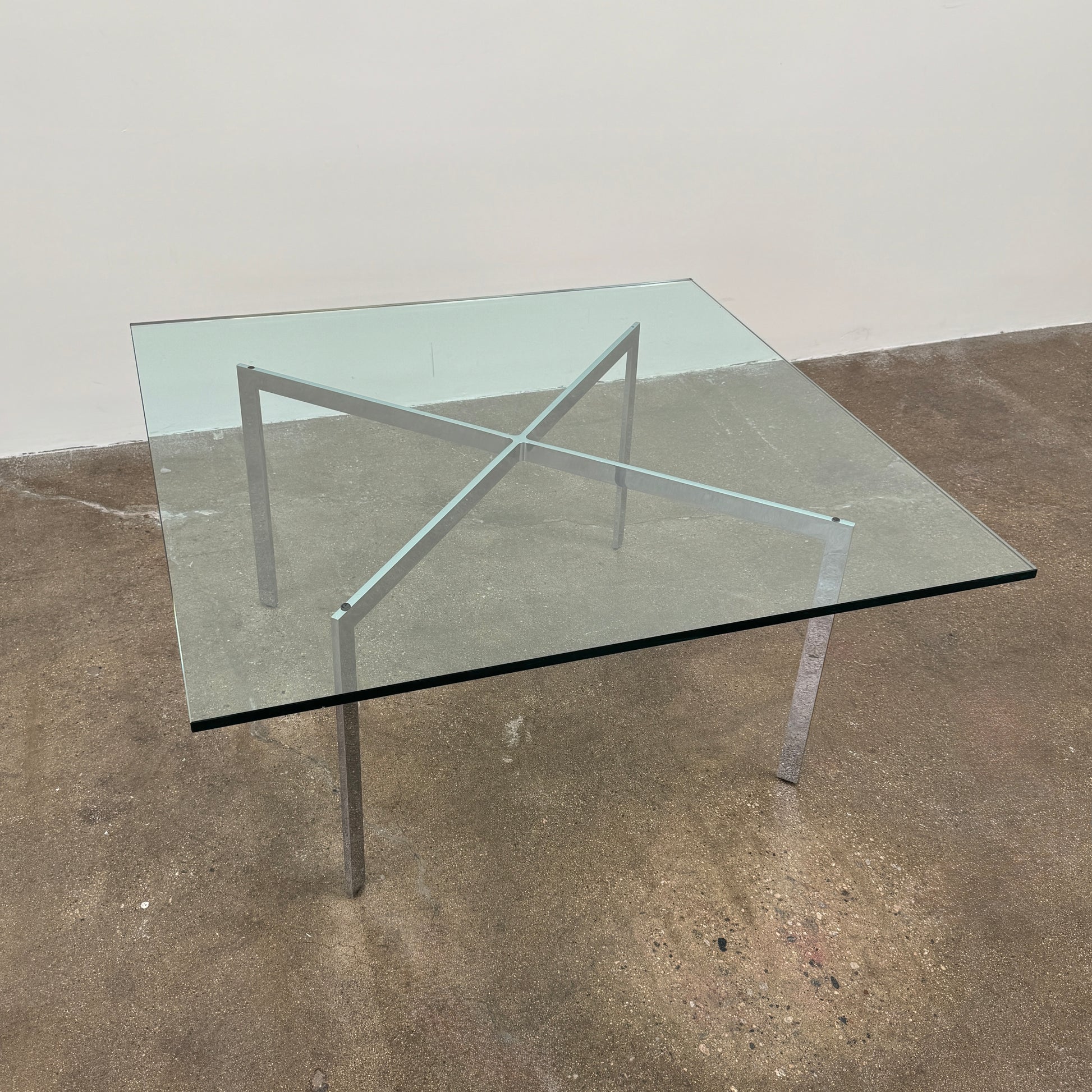 The Vintage DWR Barcelona Coffee Table by DWR features a rectangular glass top, four metal legs, and a visible metal support frame underneath.
