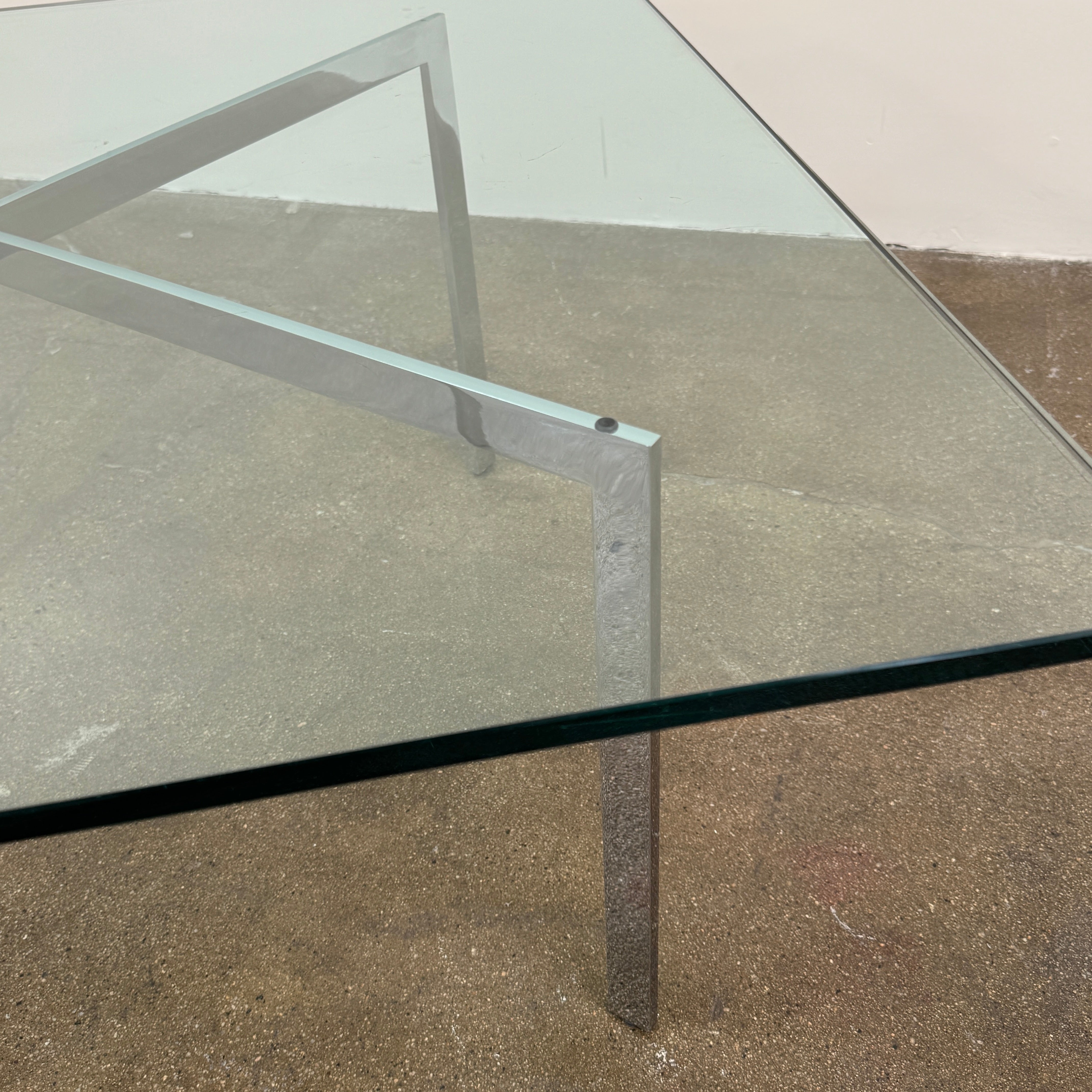 The Vintage DWR Barcelona Coffee Table by DWR features a rectangular glass top, four metal legs, and a visible metal support frame underneath.