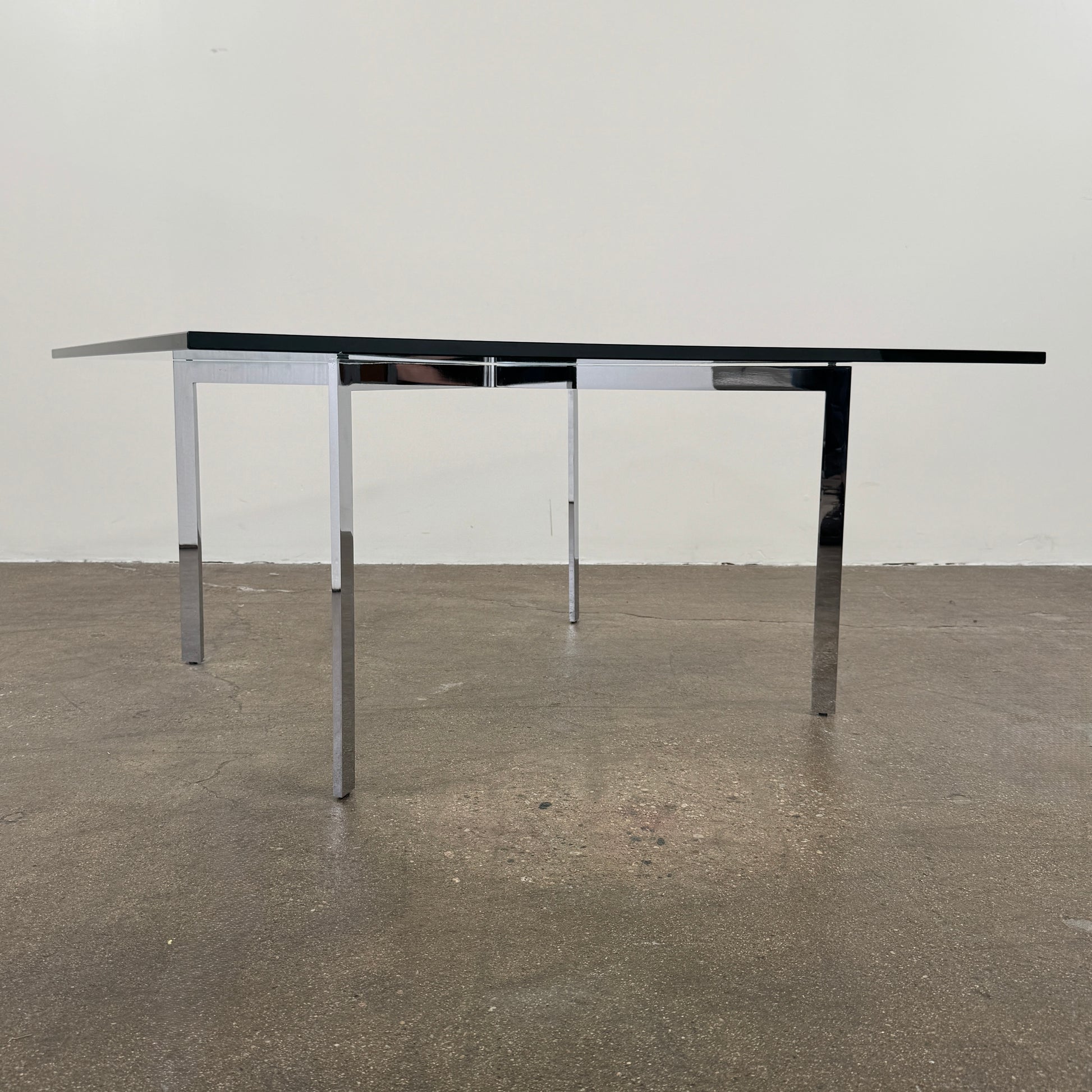 The Vintage DWR Barcelona Coffee Table by DWR features a rectangular glass top, four metal legs, and a visible metal support frame underneath.