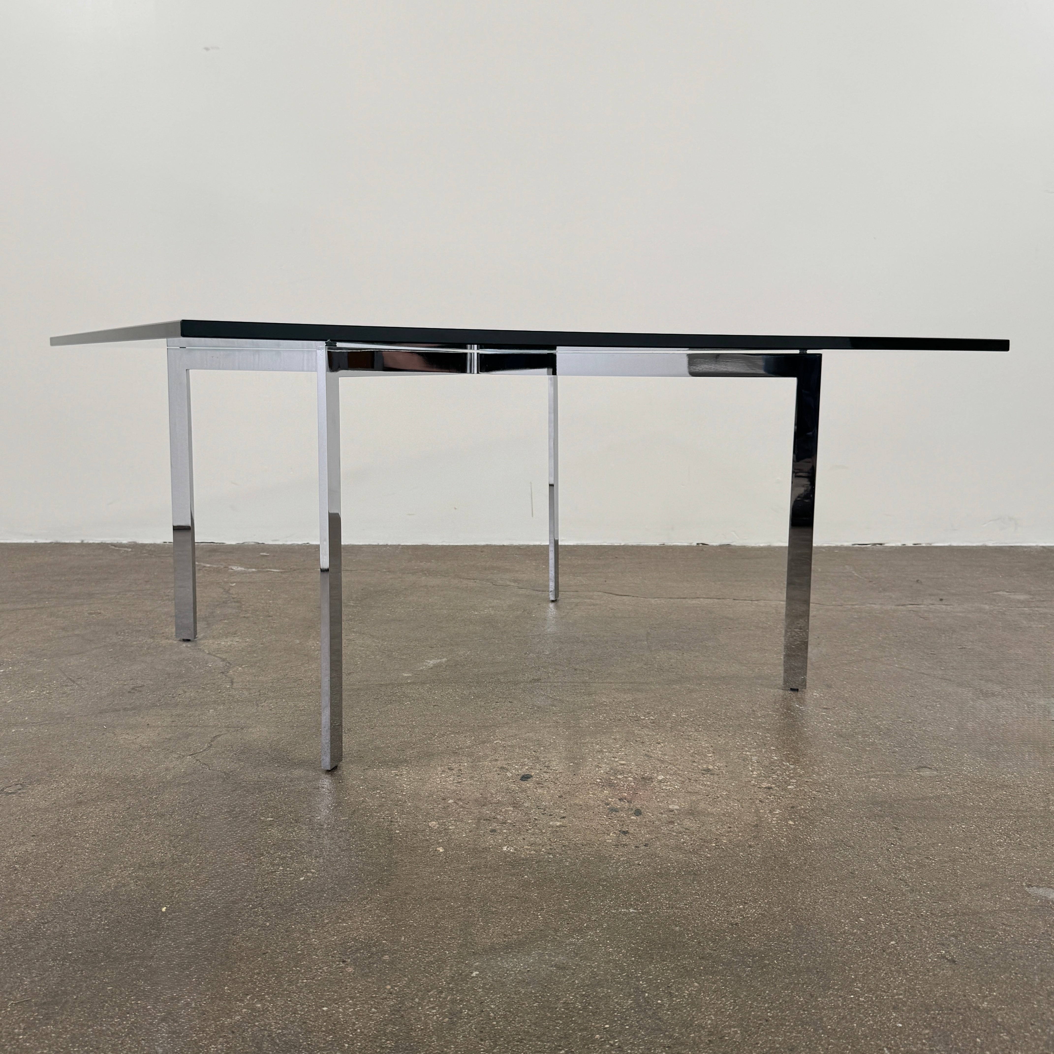 The Vintage DWR Barcelona Coffee Table by DWR features a rectangular glass top, four metal legs, and a visible metal support frame underneath.