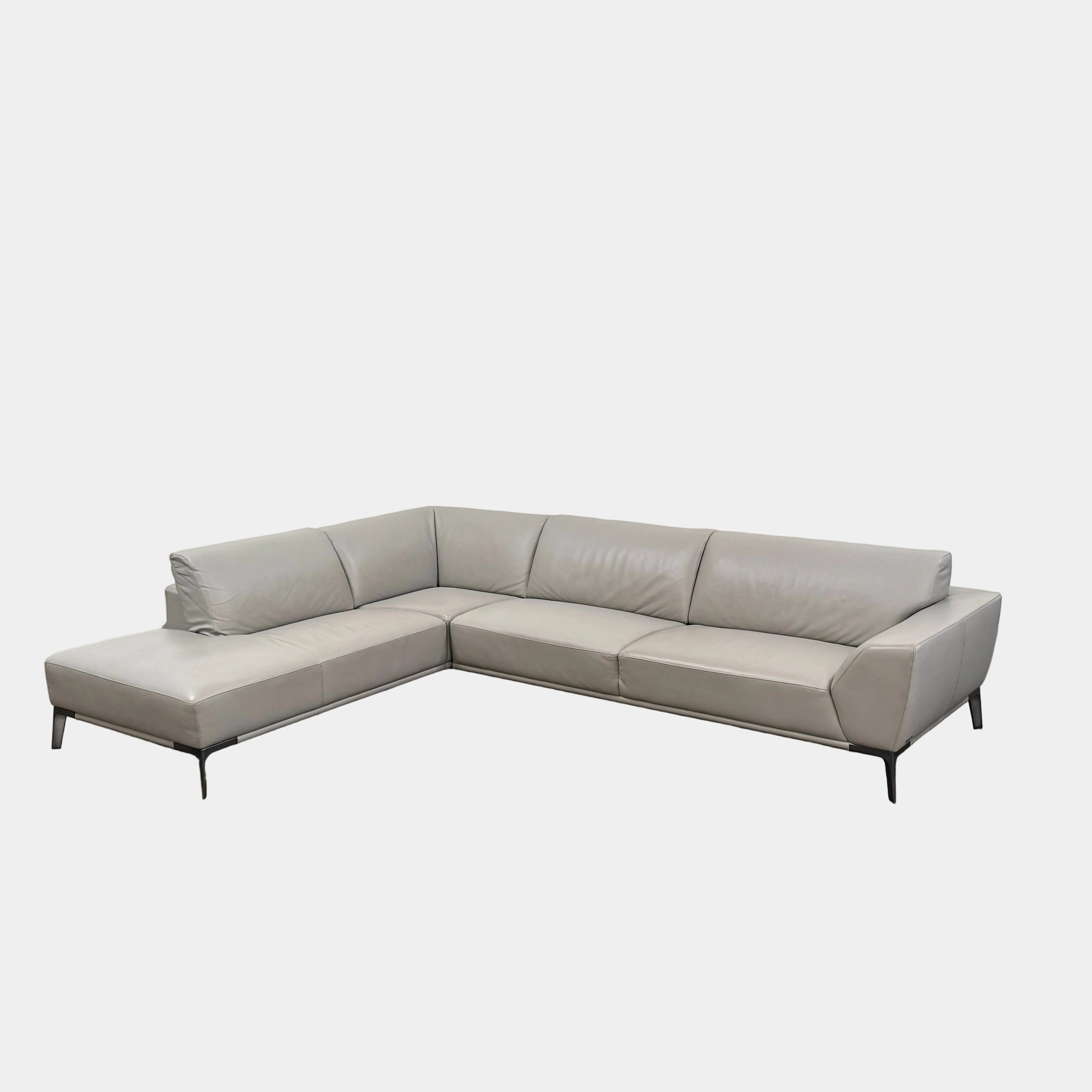 A Roche Bobois Accord Gray Leather Sectional sits in a spacious room with floor-to-ceiling windows and light wood floors, overlooking a cityscape.