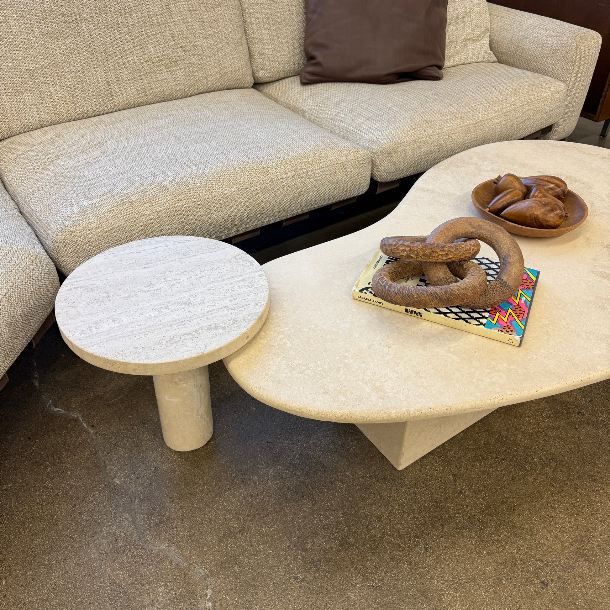 The Custom Travertine Coffee Table Set by Custom features two beige stone surfaces—one oval, one round—supported by solid travertine legs, offering sculptural elegance and modern style to any space.