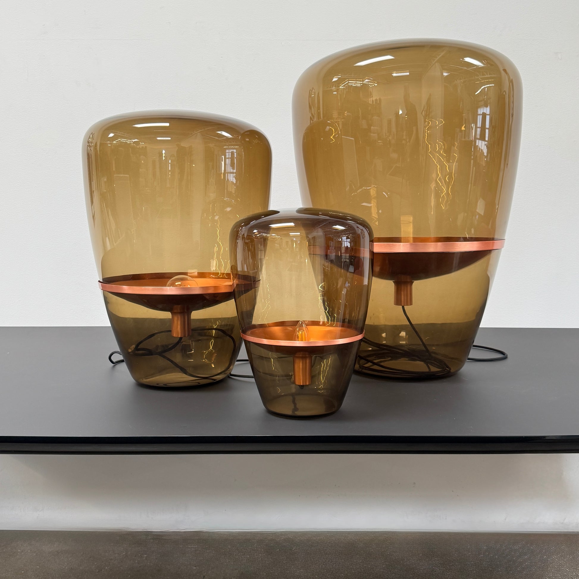 Three Brokis Balloons LED Lamps with handblown glass and copper accents are arranged side by side against a white background, highlighting their elegant sculptural design.