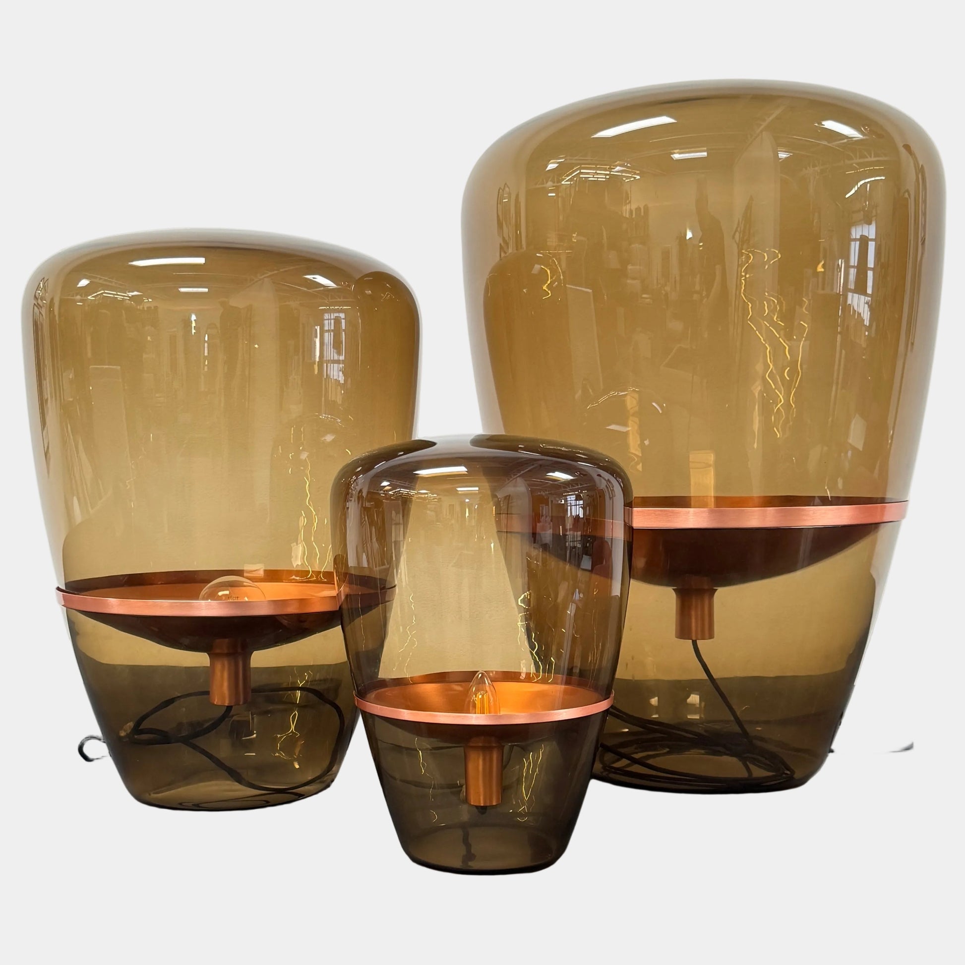 Three Brokis Balloons LED Lamps with handblown glass and copper accents are arranged side by side against a white background, highlighting their elegant sculptural design.