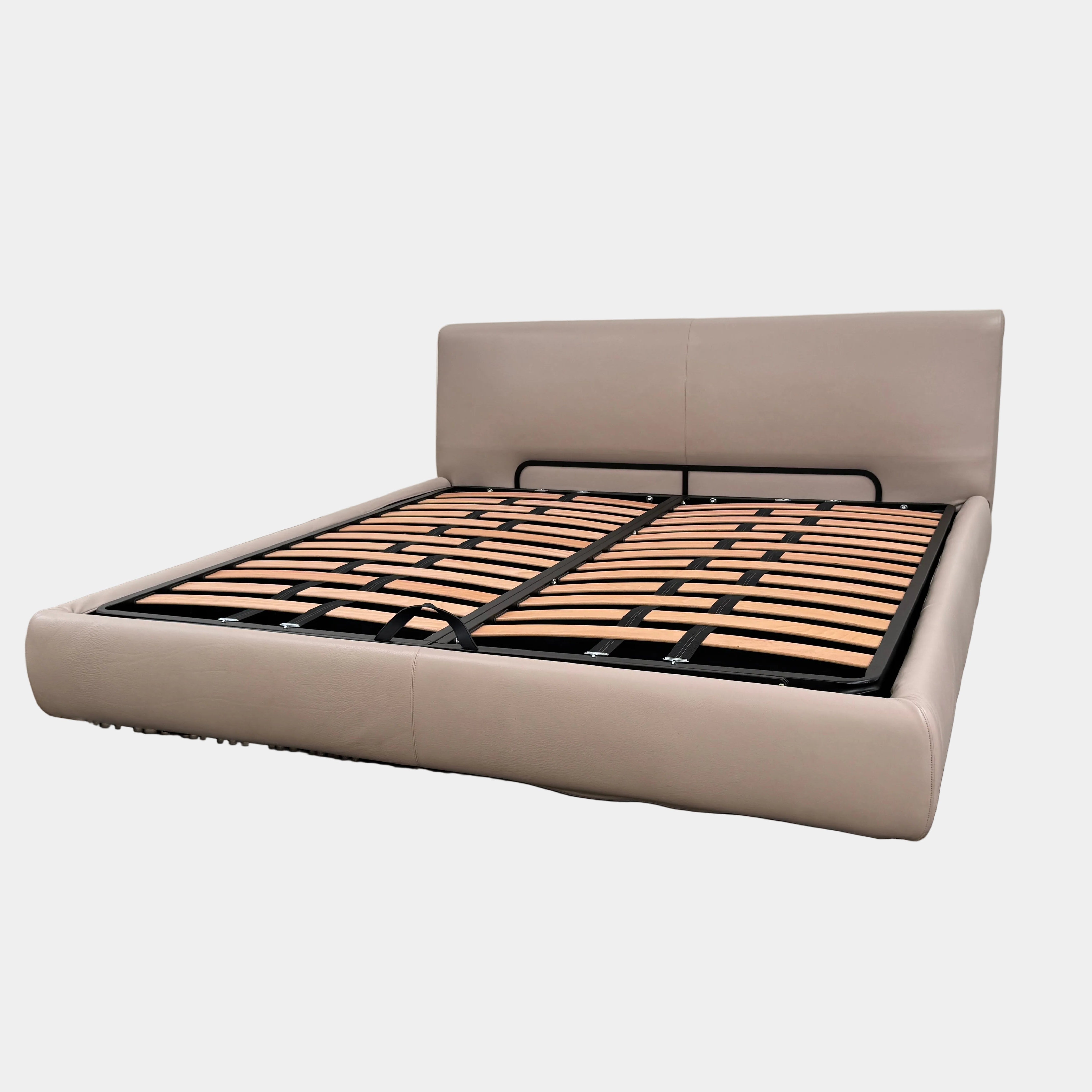 The DWR Nest King Size Leather Bed features a beige upholstered headboard and base, exposed wooden slats, and a sturdy metal support structure for enhanced durability.