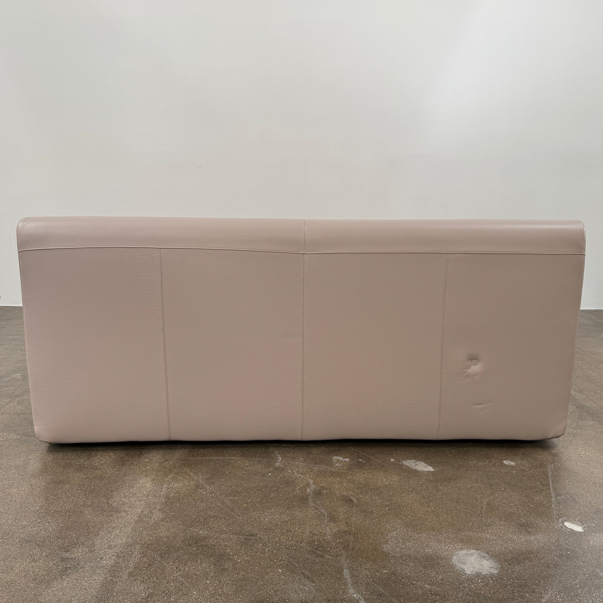 The DWR Nest King Size Leather Bed features a beige upholstered headboard and base, exposed wooden slats, and a sturdy metal support structure for enhanced durability.